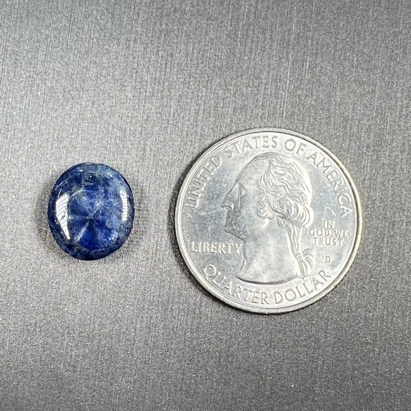 A loose, oval cabochon cut blue trapiche star sapphire stone.