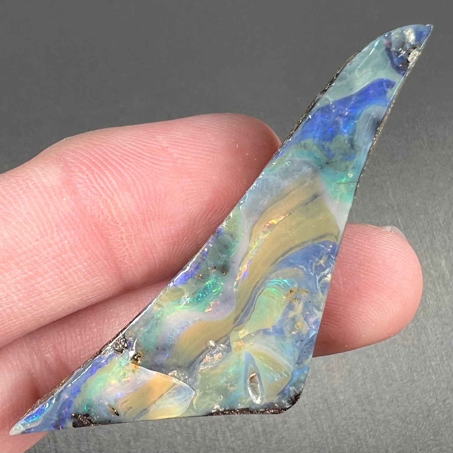 A loose, triangular shaped boulder opal stone from Queensland, Australia.