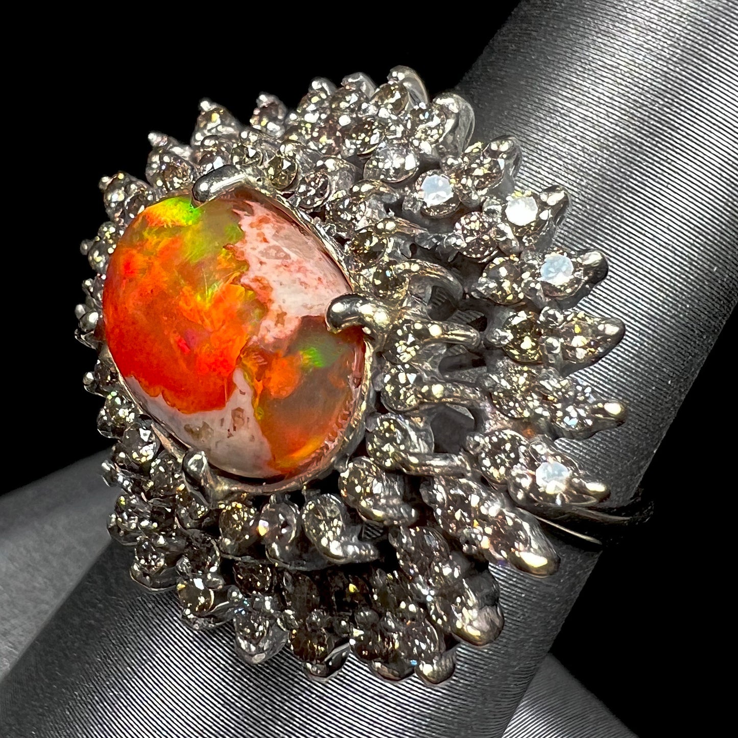 An 18k white gold orange fire opal ring set with a triple halo of diamonds.