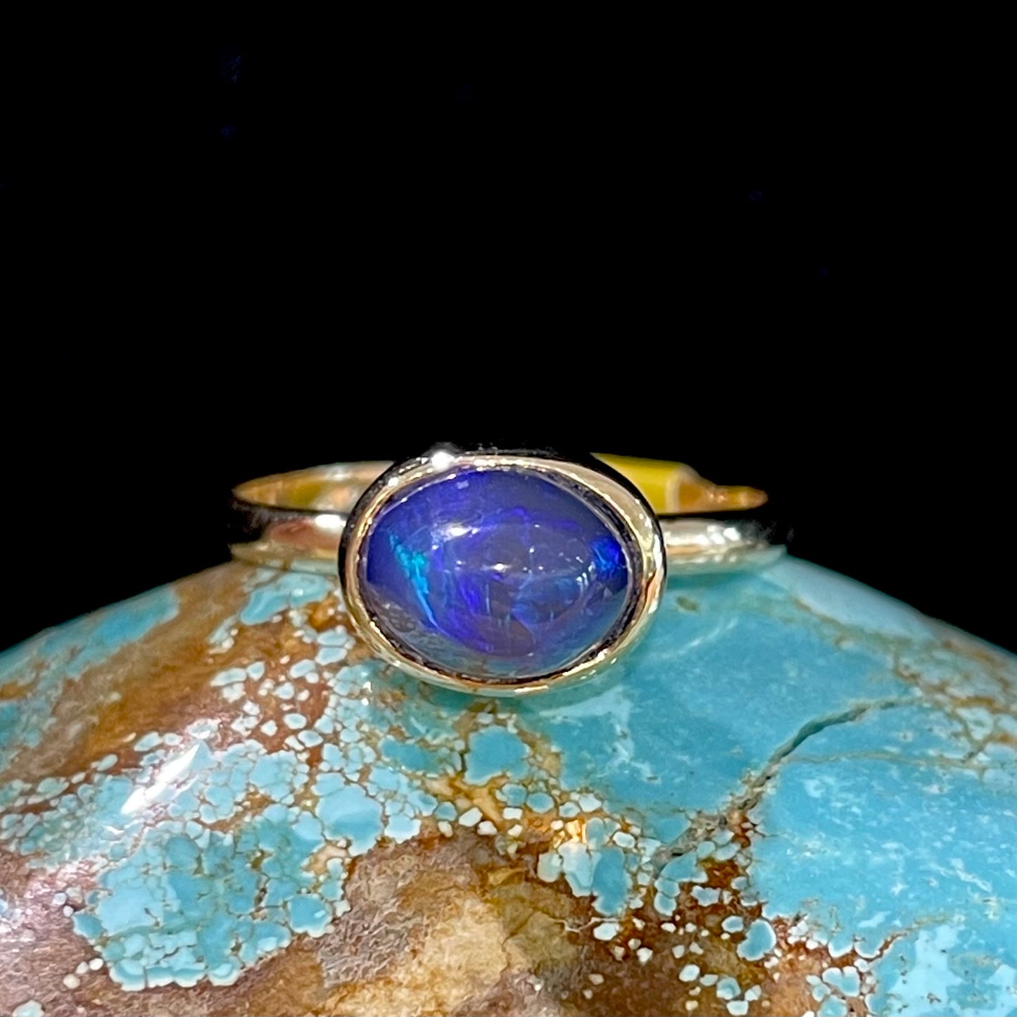 A ladies' black crystal opal solitaire ring set in yellow gold.