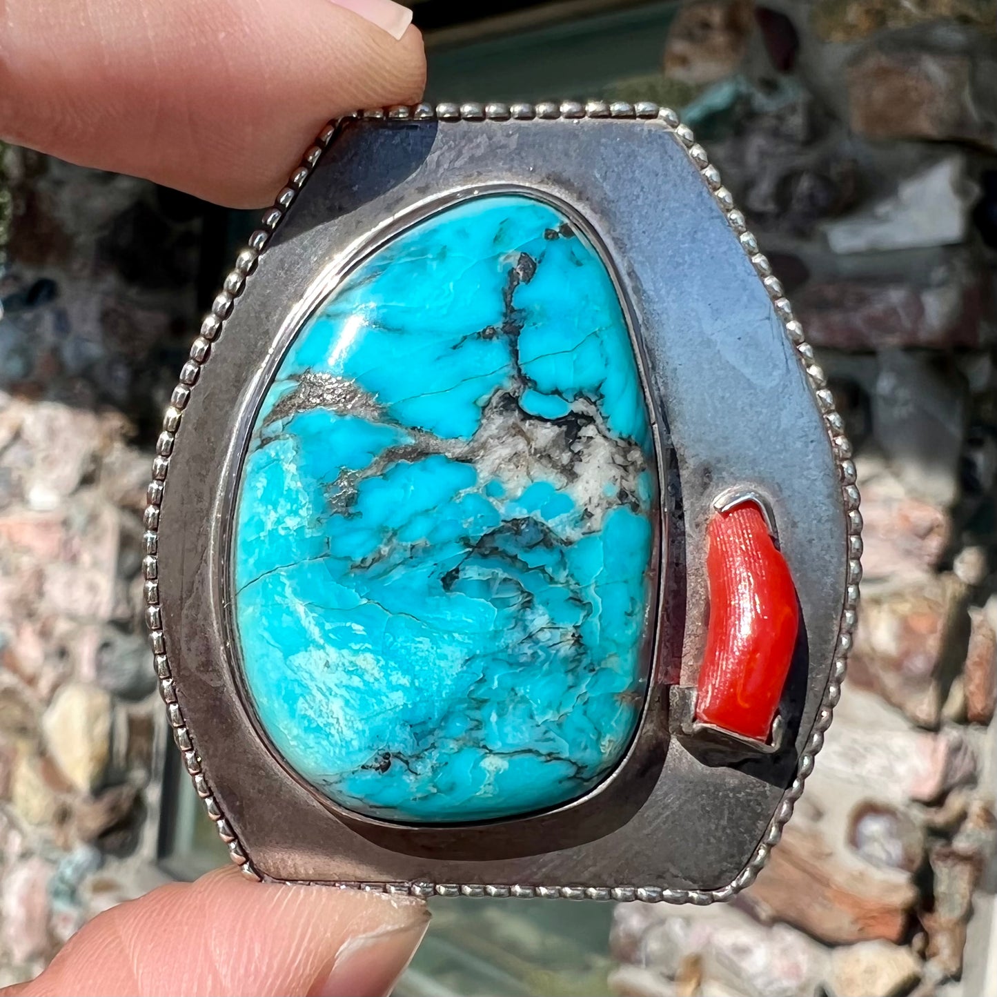 A sterling silver turquoise and polished coral branch pendant. The back of the piece is signed "A.H."