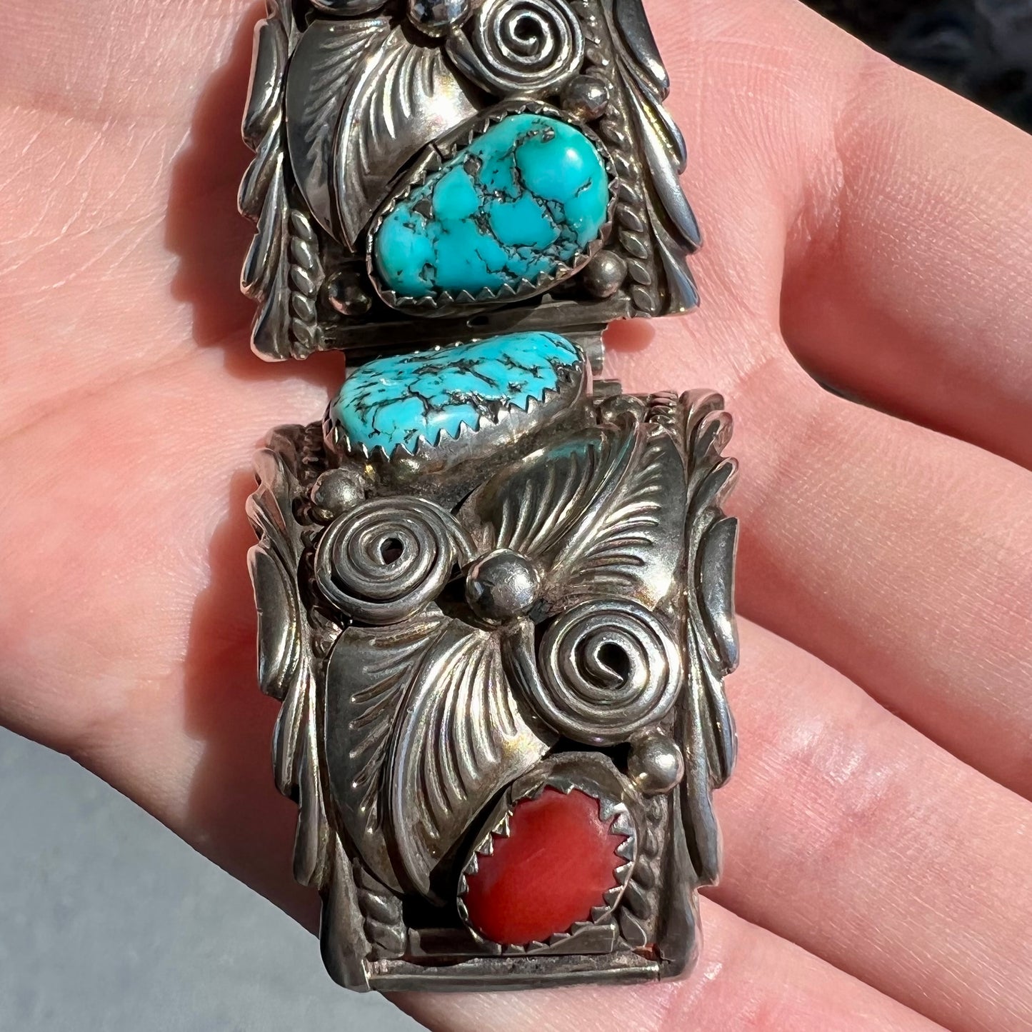 A pair of sterling silver watch cuffs set with turquoise and coral stones.