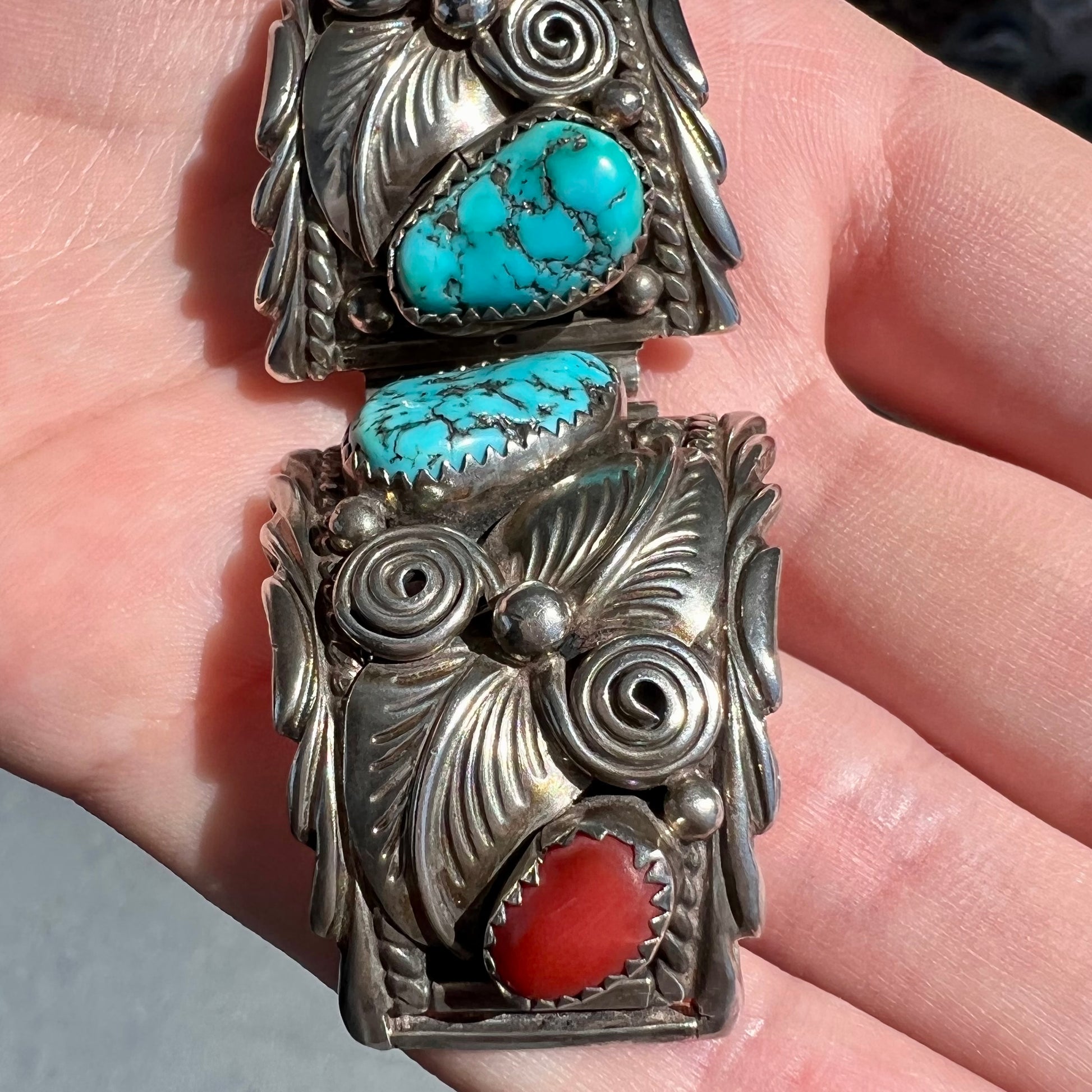 A pair of sterling silver watch cuffs set with turquoise and coral stones.