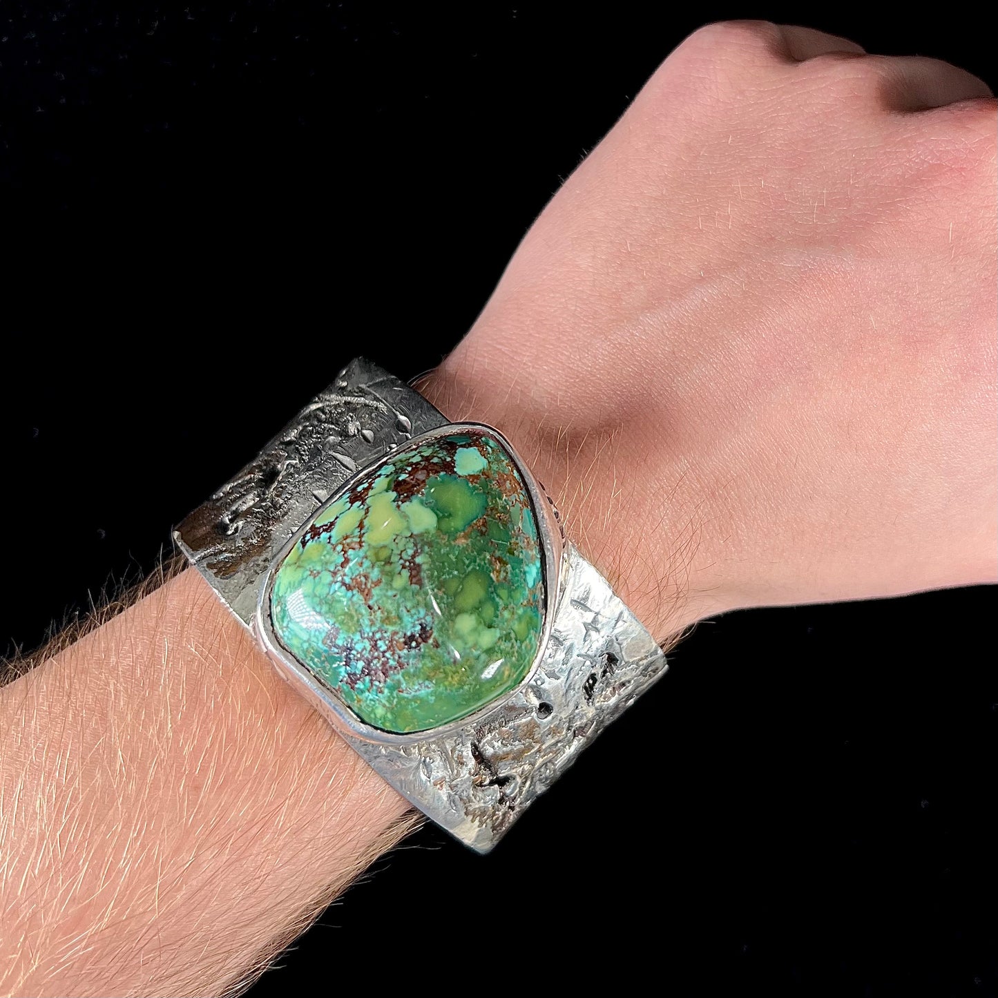 A men's sterling silver cuff bracelet infused with copper and set with a green turquoise stone from Carico Lake, Nevada.