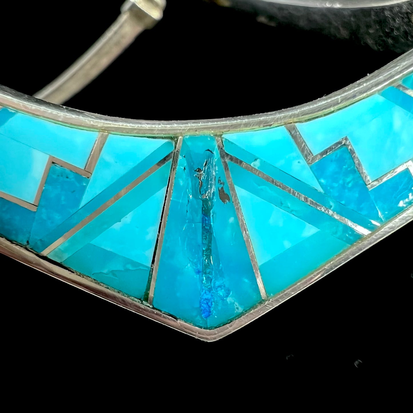 A silver omega style necklace inlaid with turquoise under the watch of David Rosales.