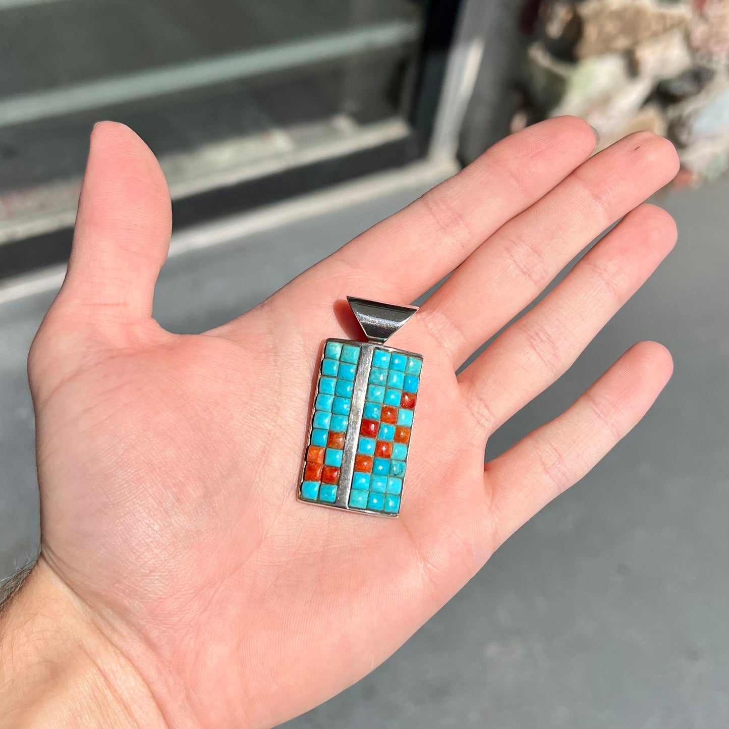 A silver pendant set with square cabochon cut turquoise and coral stones. The piece is stamped "DTR CHINA".