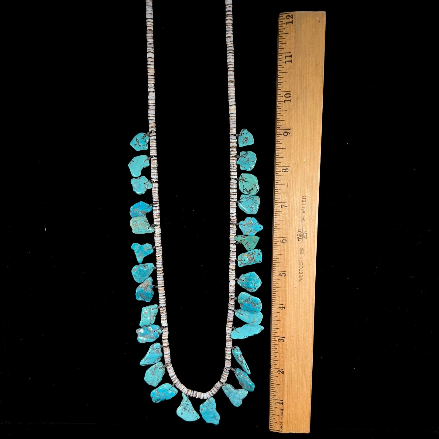 A Santo Domingo puka shell bead necklace with drilled turquoise nuggets attached.