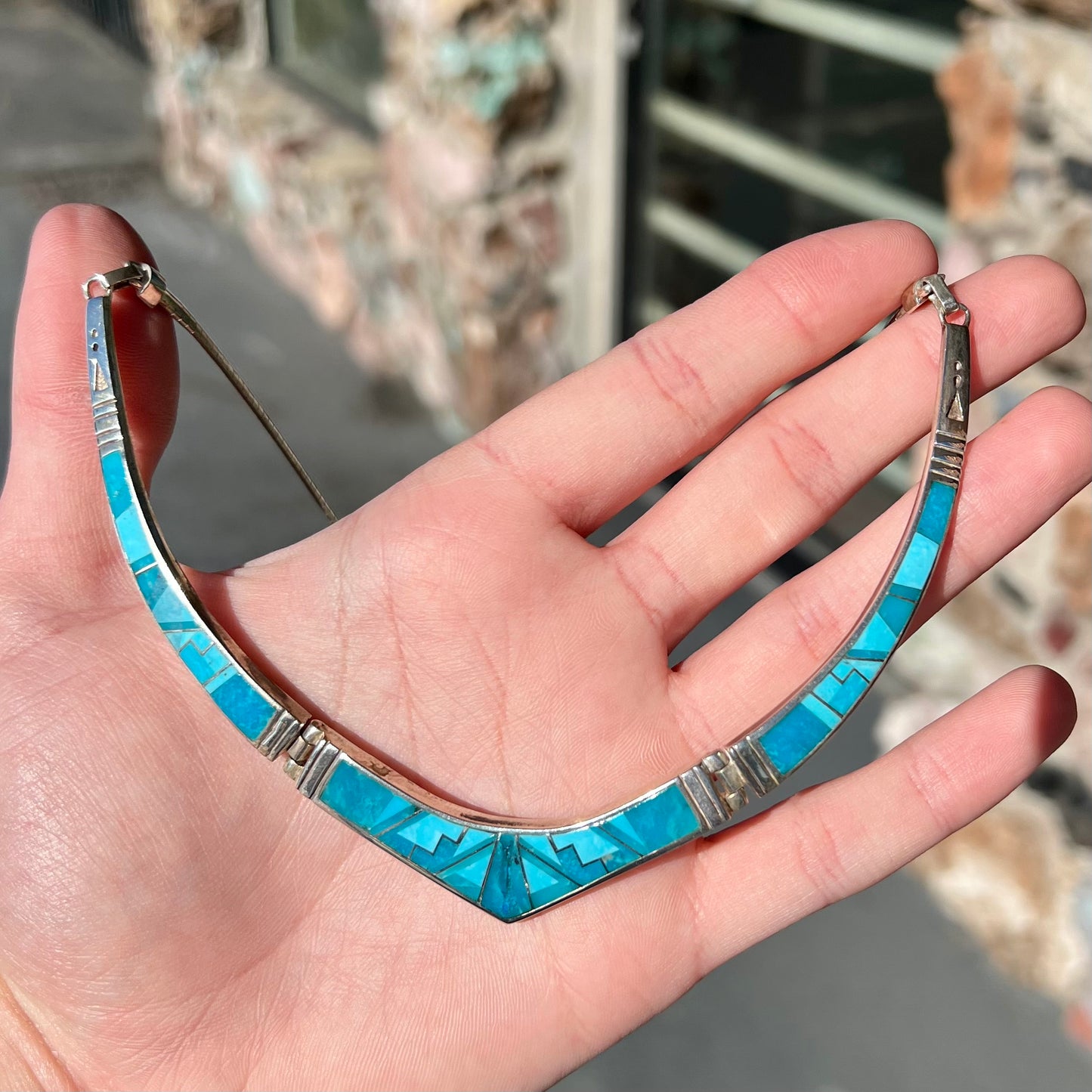 A silver omega style necklace inlaid with turquoise under the watch of David Rosales.