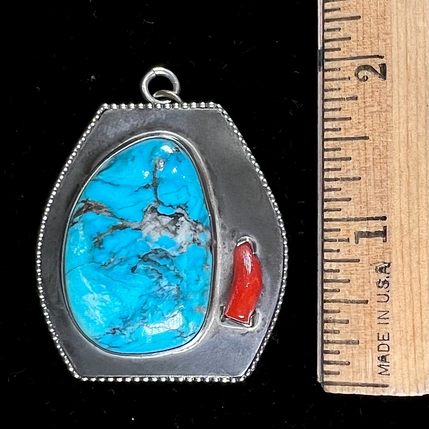 A sterling silver turquoise and polished coral branch pendant. The back of the piece is signed "A.H."