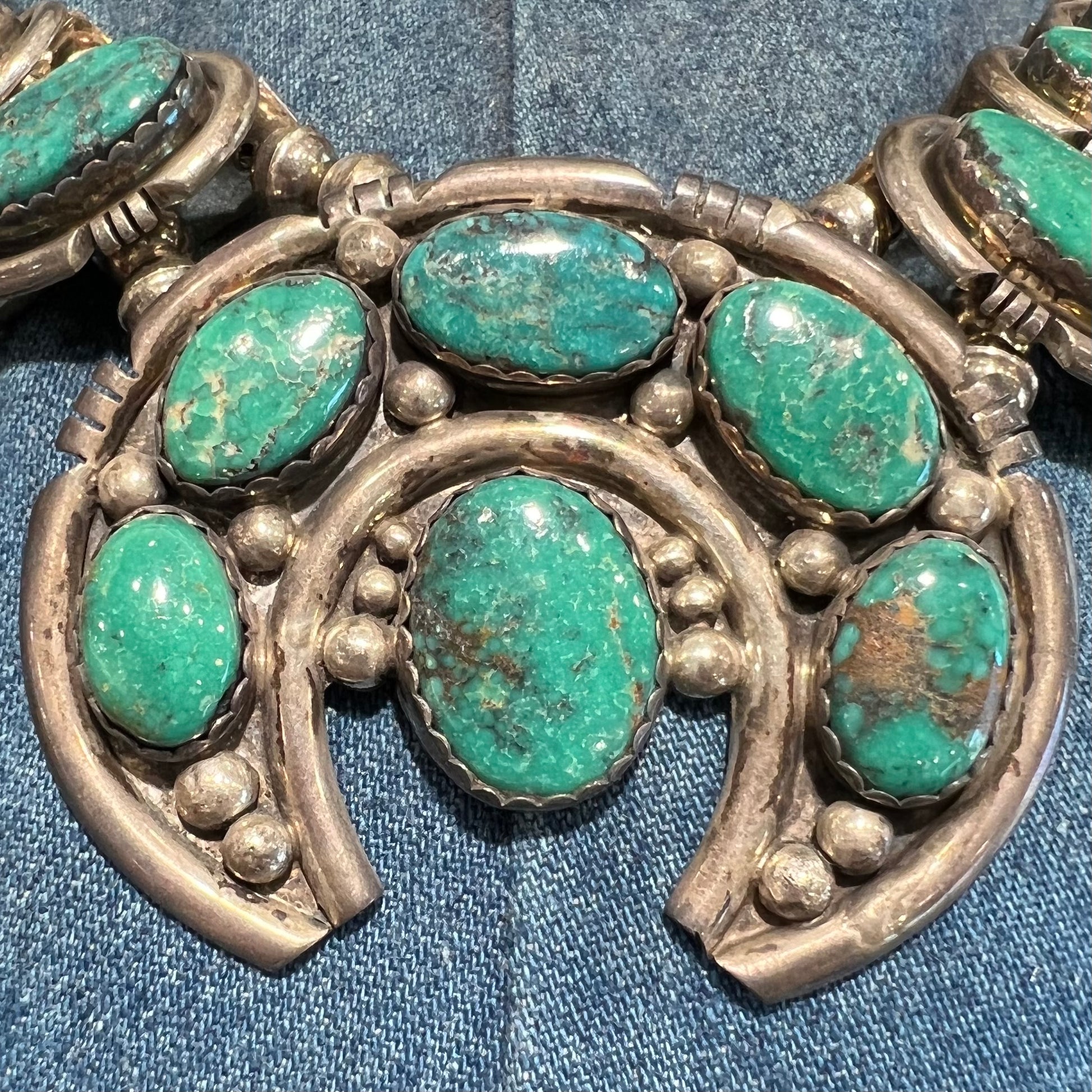 A silver Kingman turquoise squash blossom necklace.  The necklace is made with handmade Navajo pearls.