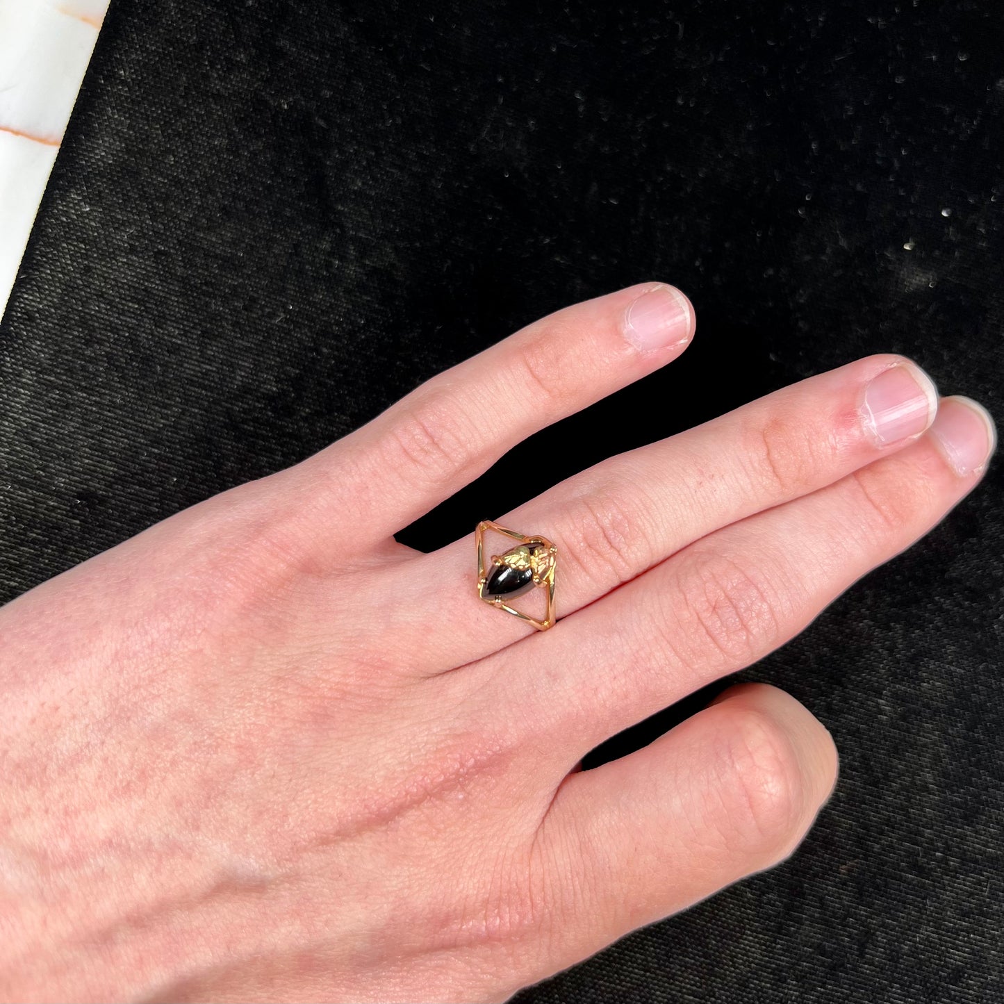 A split shank Black Hills gold ring set with a cabochon marquise cut black onyx.
