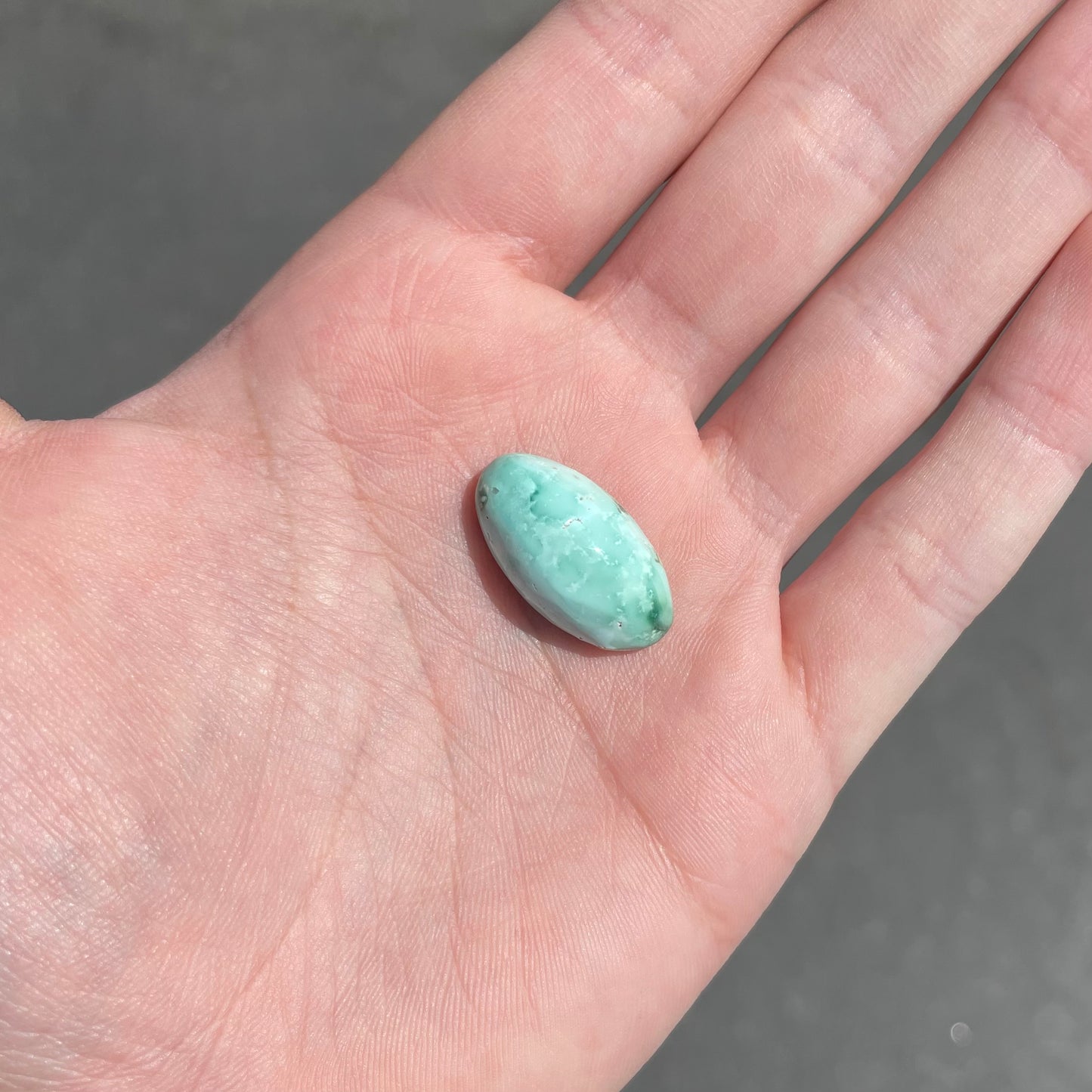 A loose, oval cabochon cut variscite stone from Utah, USA.