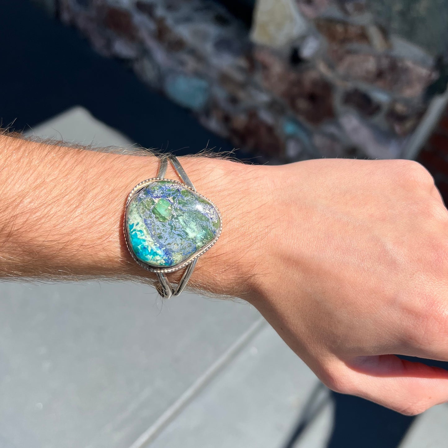 A handmade sterling silver cuff bracelet set with a single stone formed from variscite, chrysocolla, and azurite.