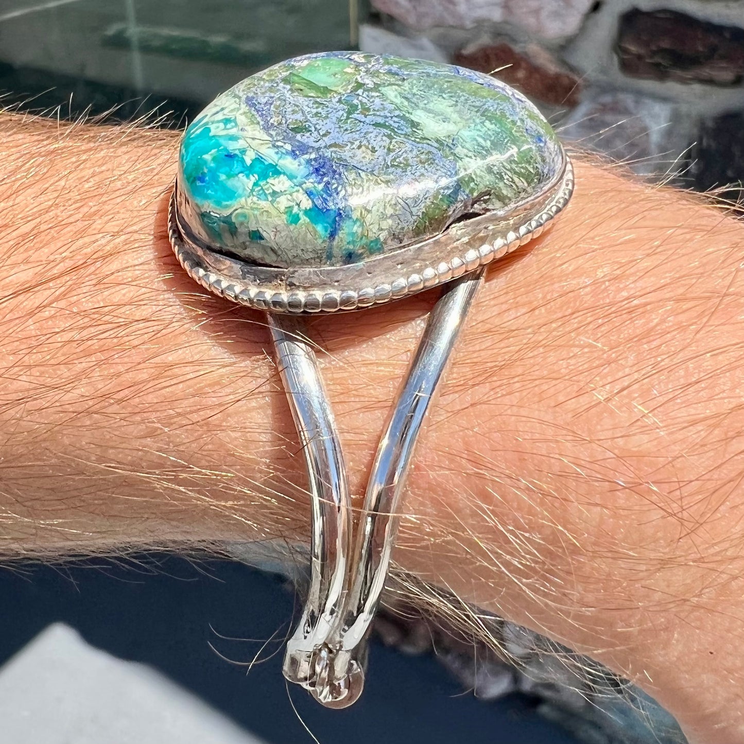 A handmade sterling silver cuff bracelet set with a single stone formed from variscite, chrysocolla, and azurite.