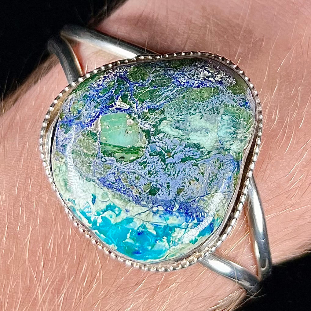 A handmade sterling silver cuff bracelet set with a single stone formed from variscite, chrysocolla, and azurite.