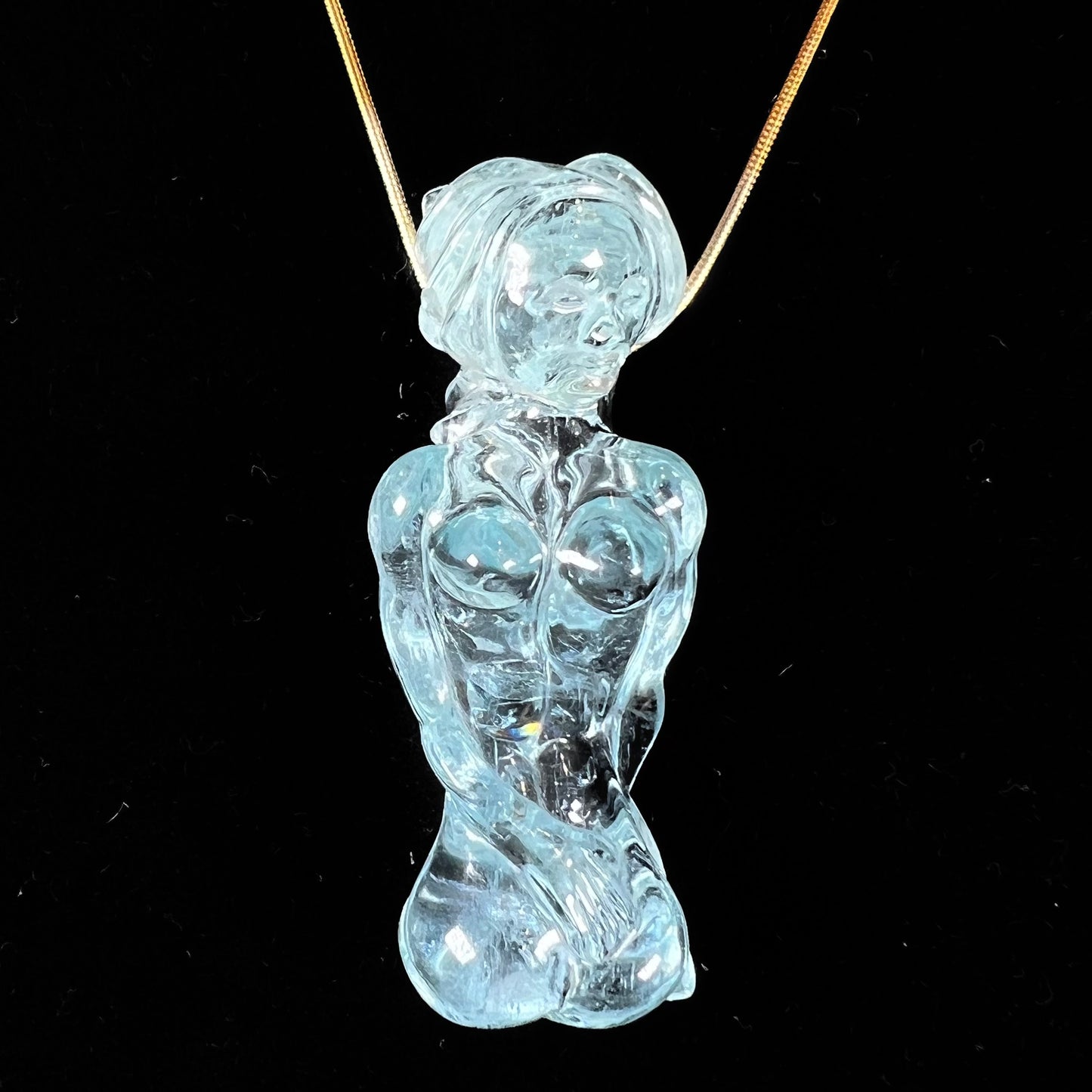 A stone woman figure carved from a blue aquamarine crystal.  The piece resembles Venus Gummi de Milo.