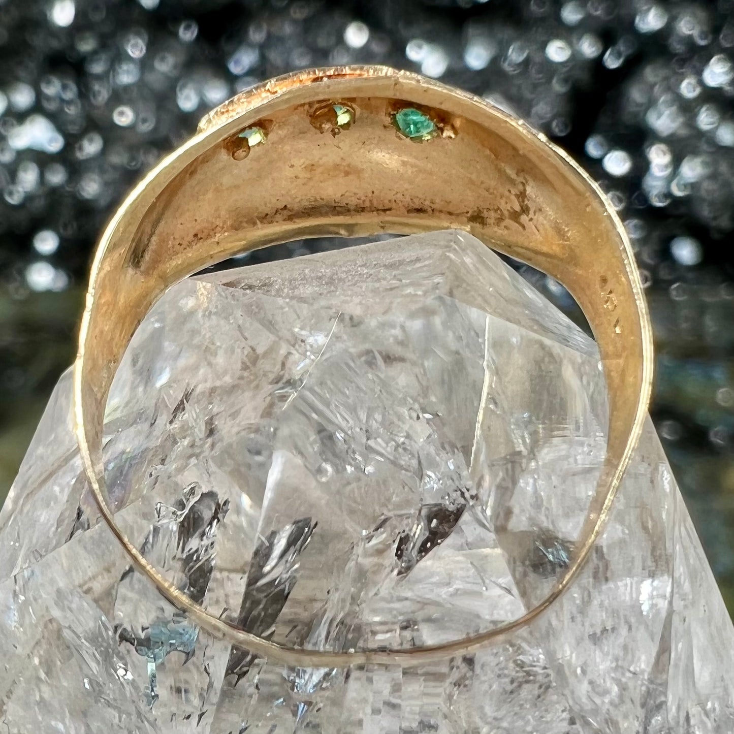 A 1920's style yellow gold three stone round cut emerald ring.