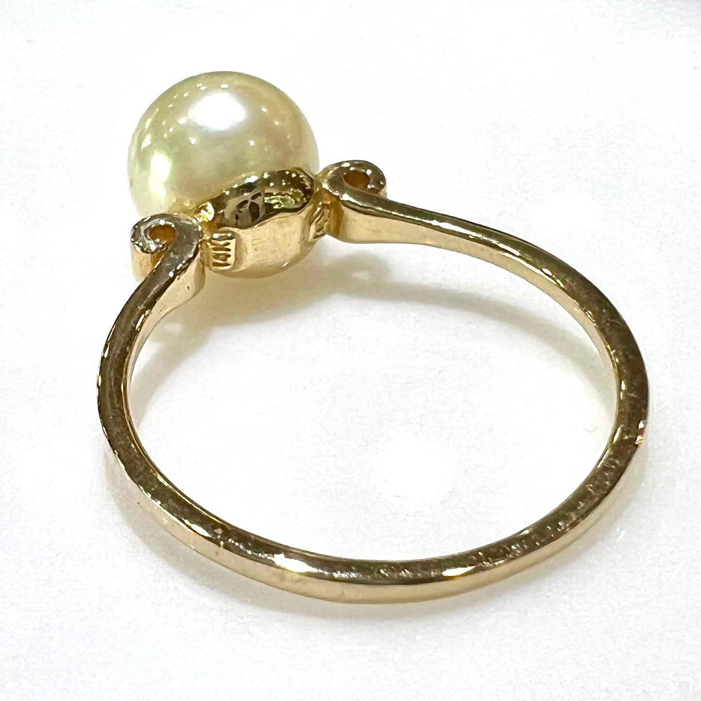 A simple, vintage, yellow gold pearl ring set with two side diamonds.