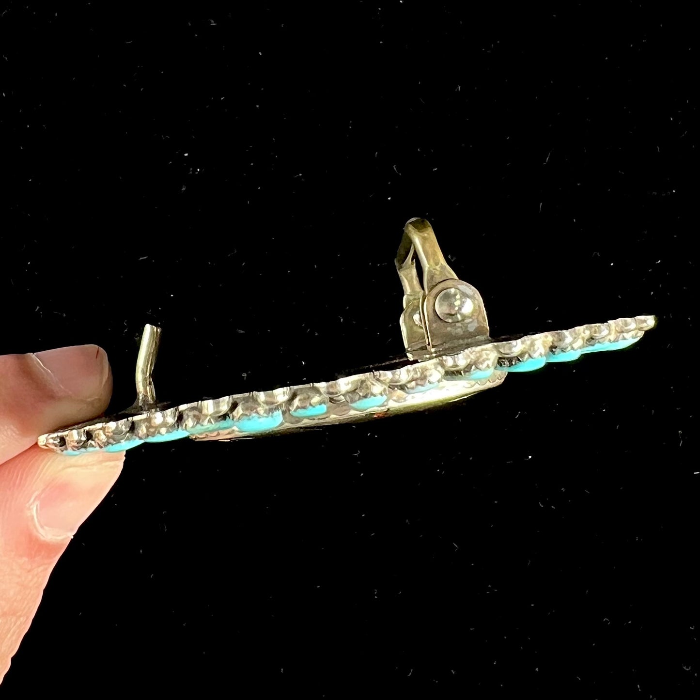 A unisex sterling silver belt buckle featuring the motif of a stone inlaid hummingbird set with petit point turquoise accents, handmade by Navajo artist, Leo G. Harvey.