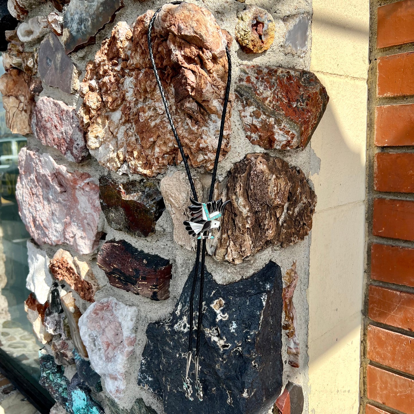 A sterling silver Zuni Indian-made bolo tie featuring the motif of three flying eagles inlaid with natural stones.