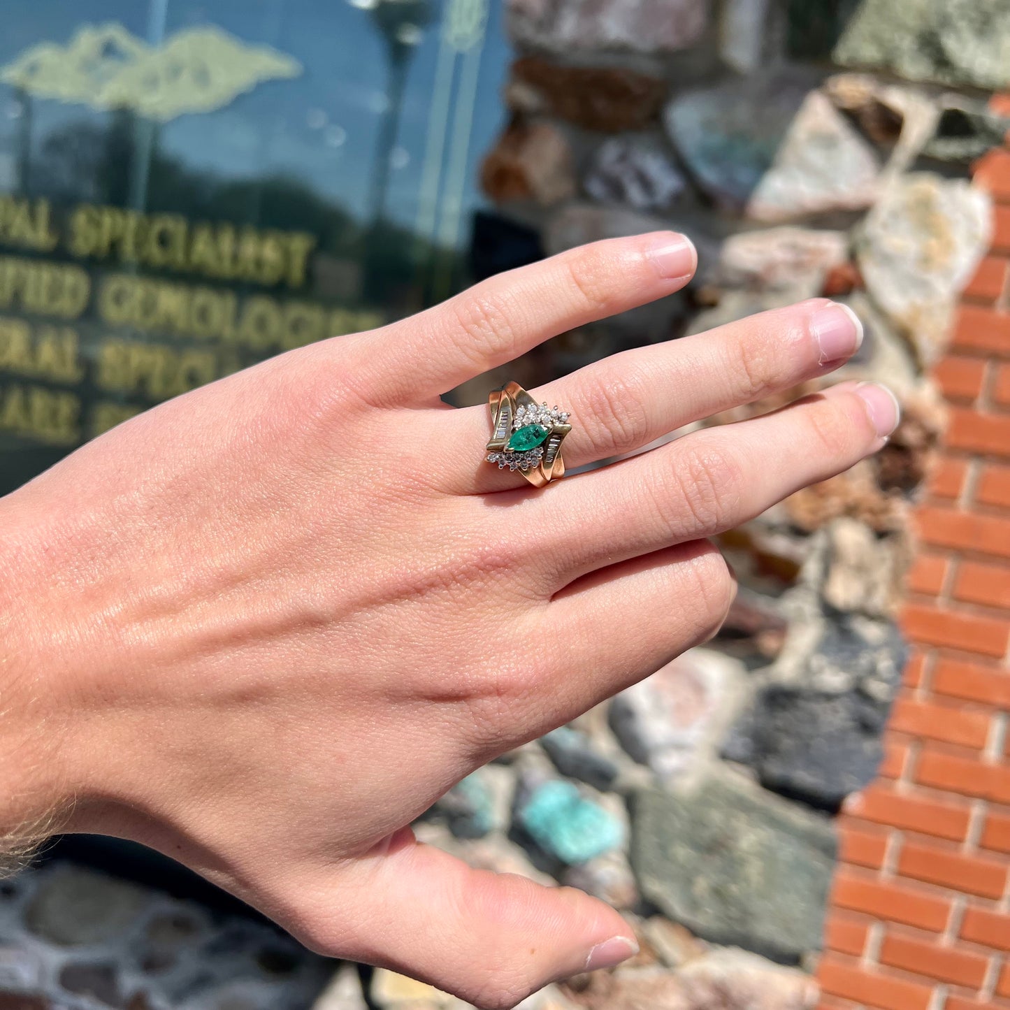 A yellow gold marquise cut emerald and diamond ring. The diamonds are prong set round cuts and channel set baguette cuts.