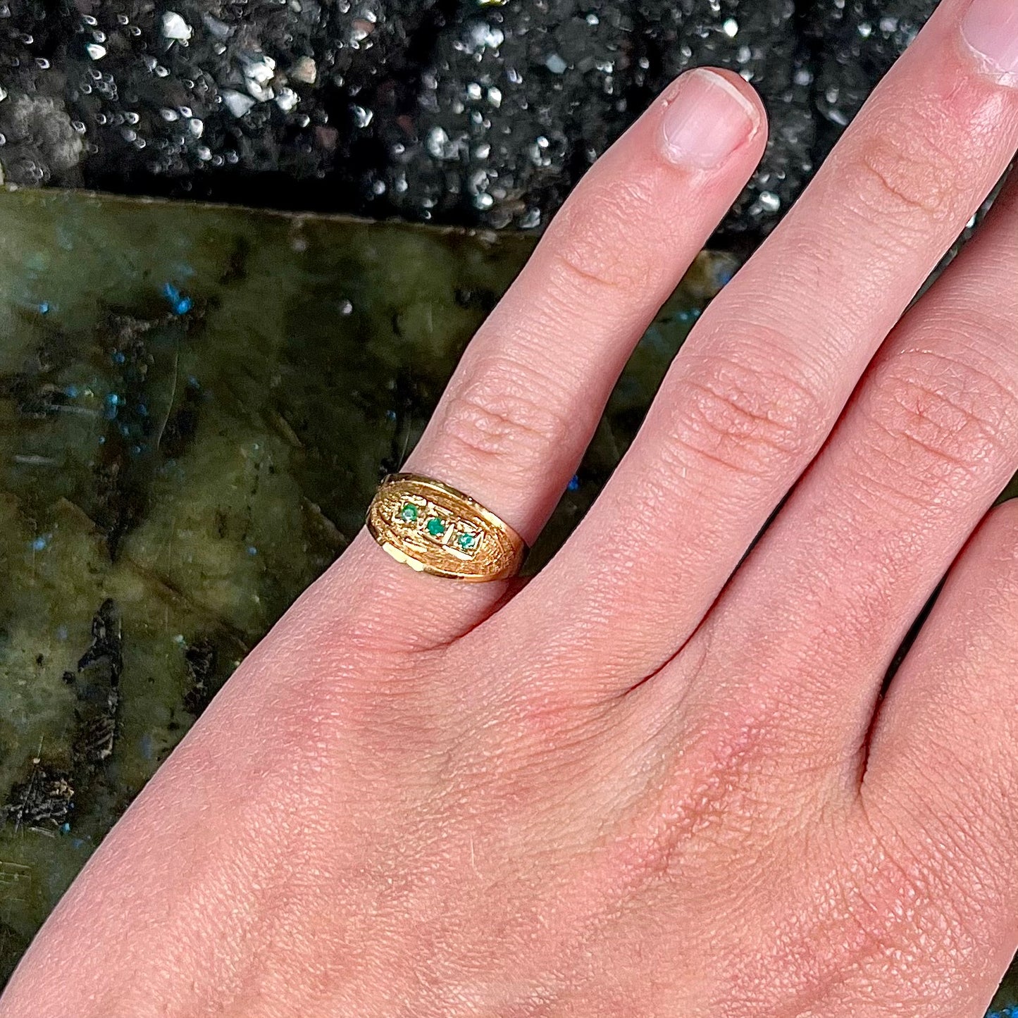 A 1920's style yellow gold three stone round cut emerald ring.