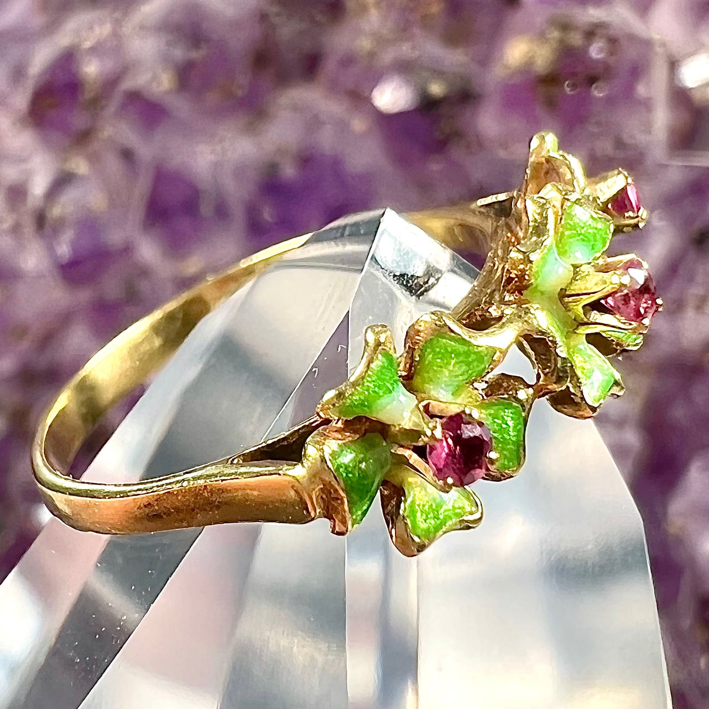 A gold ladies' ring in the motif of three flowers set with round ruby centers and green enameled petals.