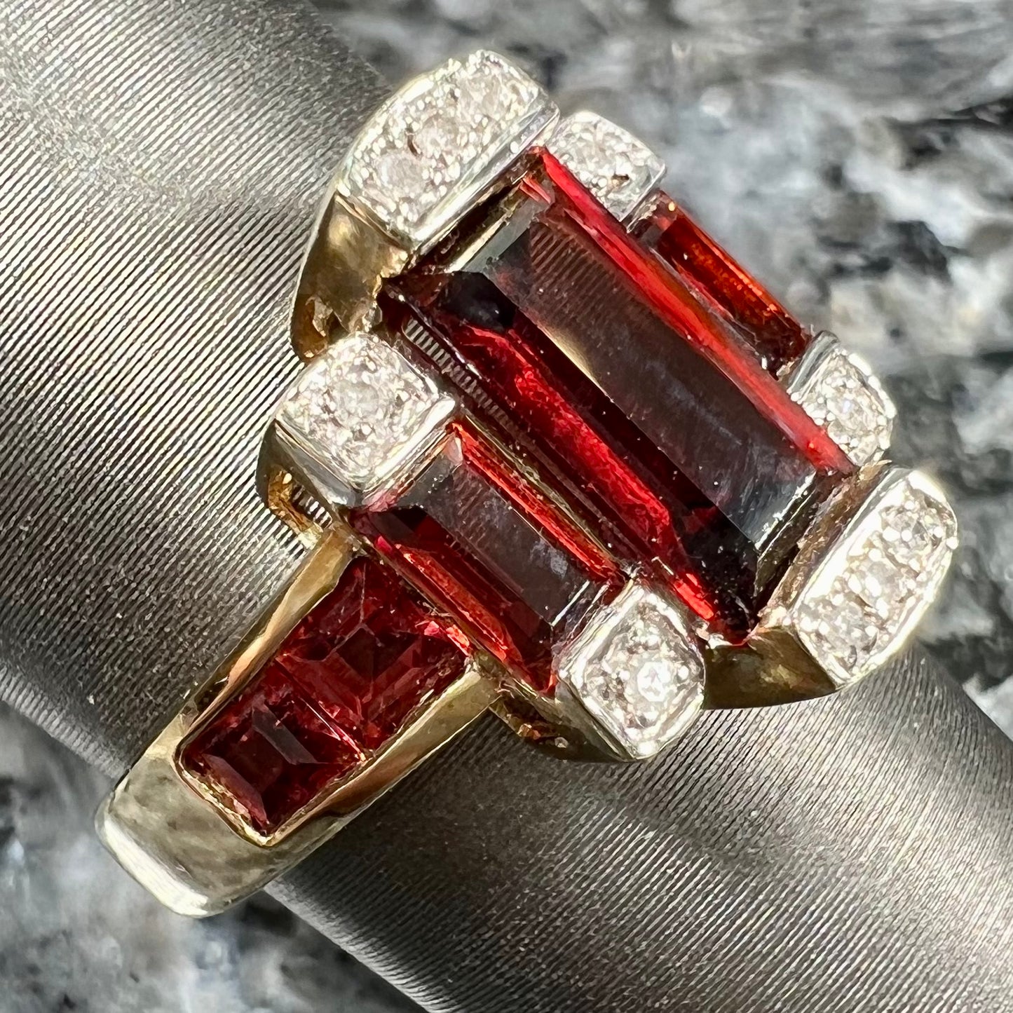 An Art Deco style emerald cut garnet and diamond ring cast in yellow gold.