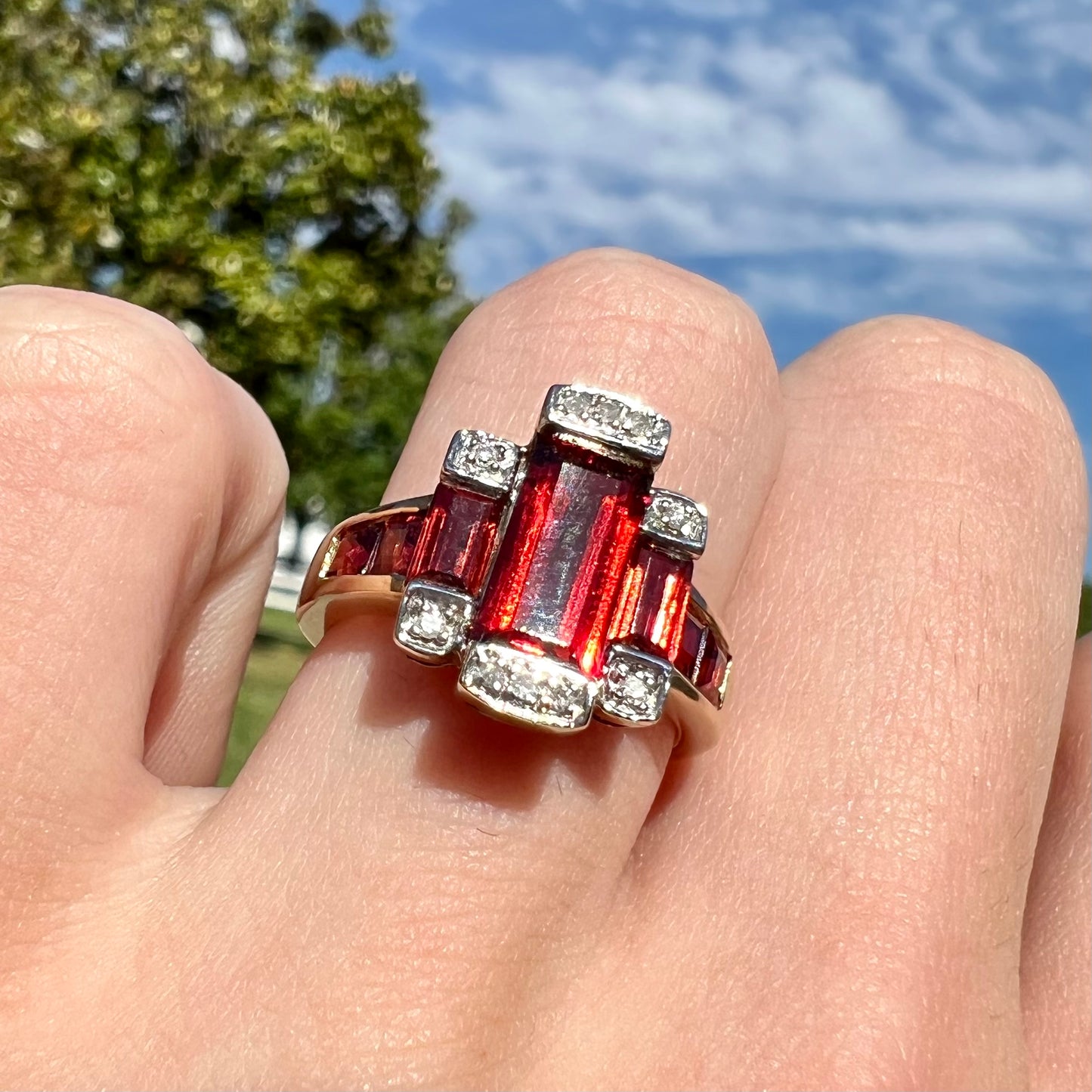 An Art Deco style emerald cut garnet and diamond ring cast in yellow gold.