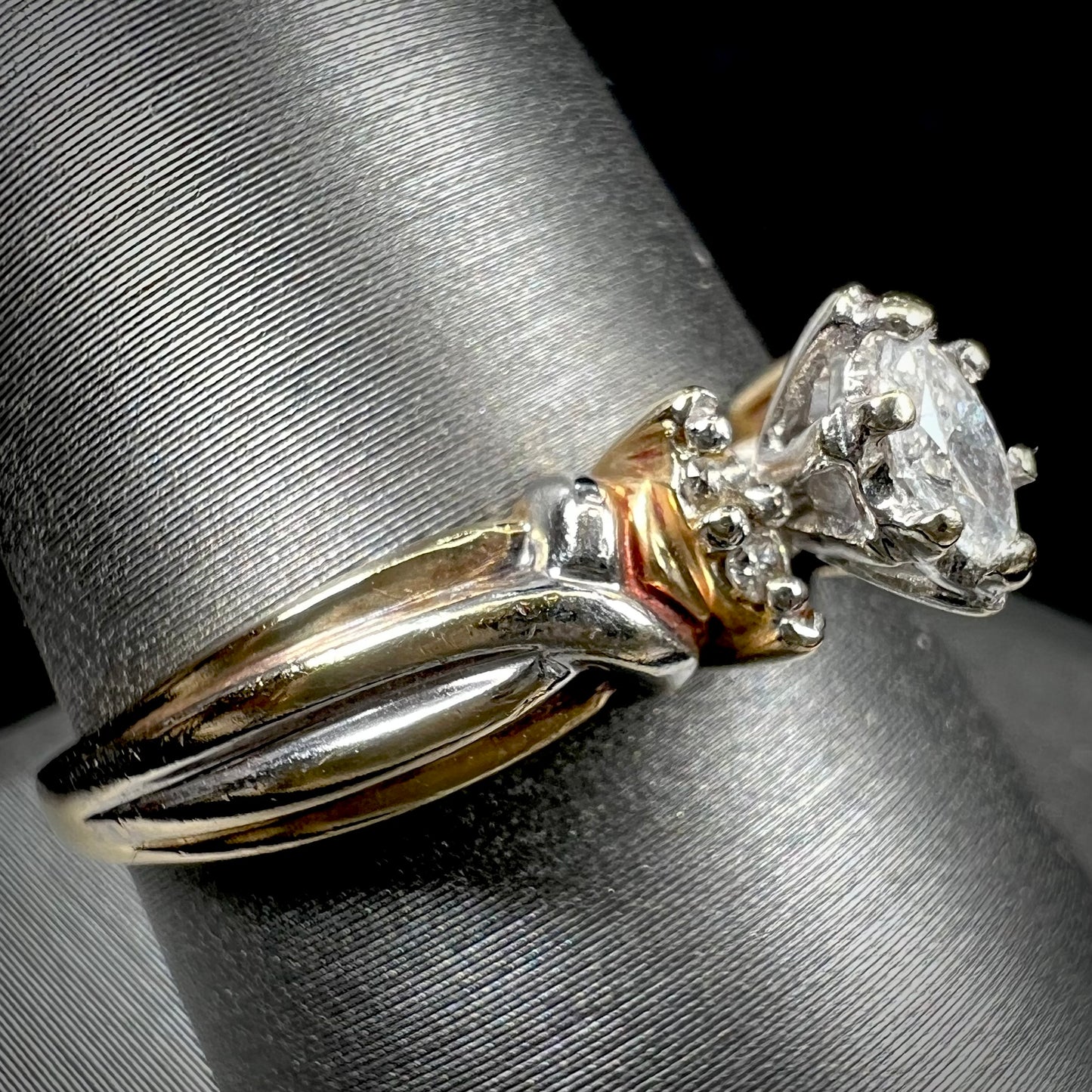 A ladies' two-tone white and yellow gold marquise cut diamond enagagement ring. There are round diamond accents.