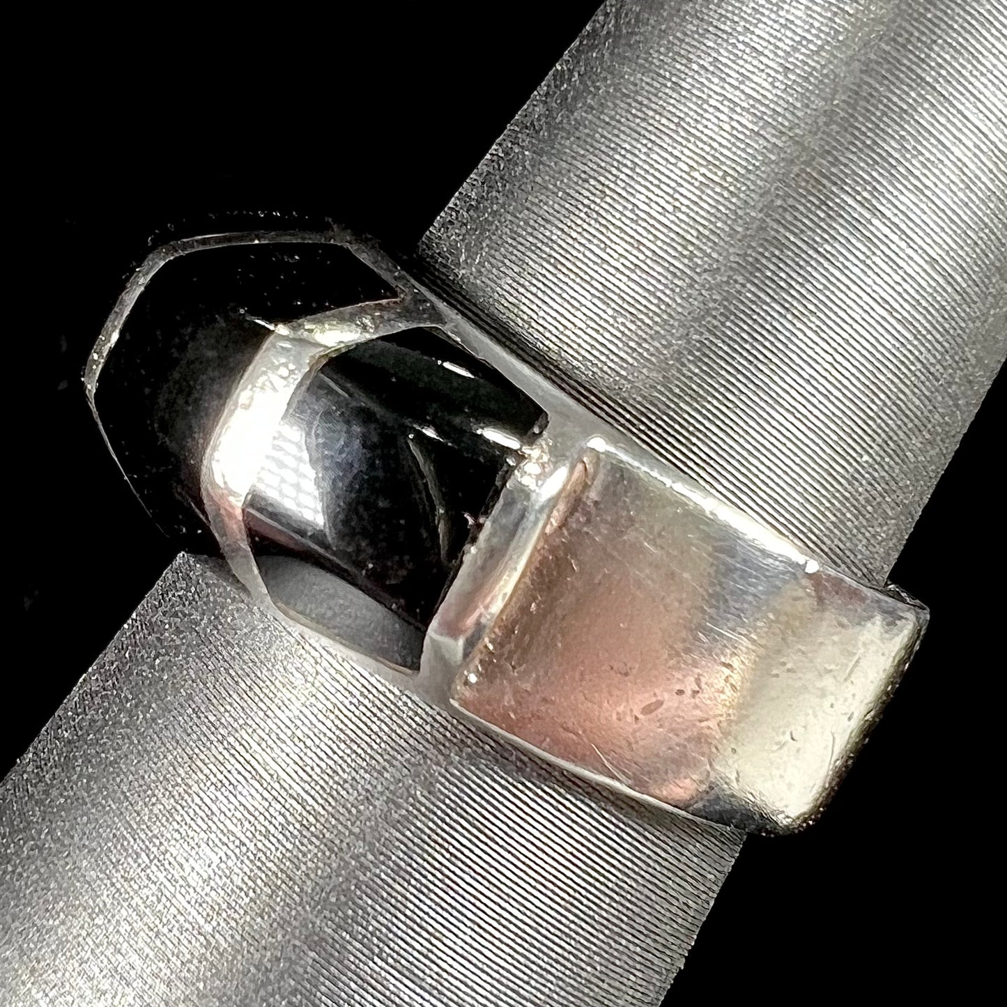 A sterling silver ring inlaid with onyx, turquoise, coral, lapis lazuli, and mother of pearl stones.
