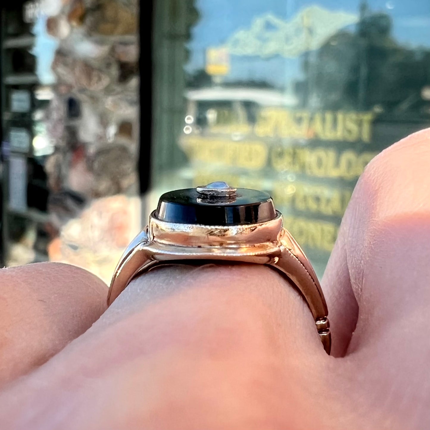 A yellow gold onyx ring set with a round cabochon cut opal bezel set into the onyx.