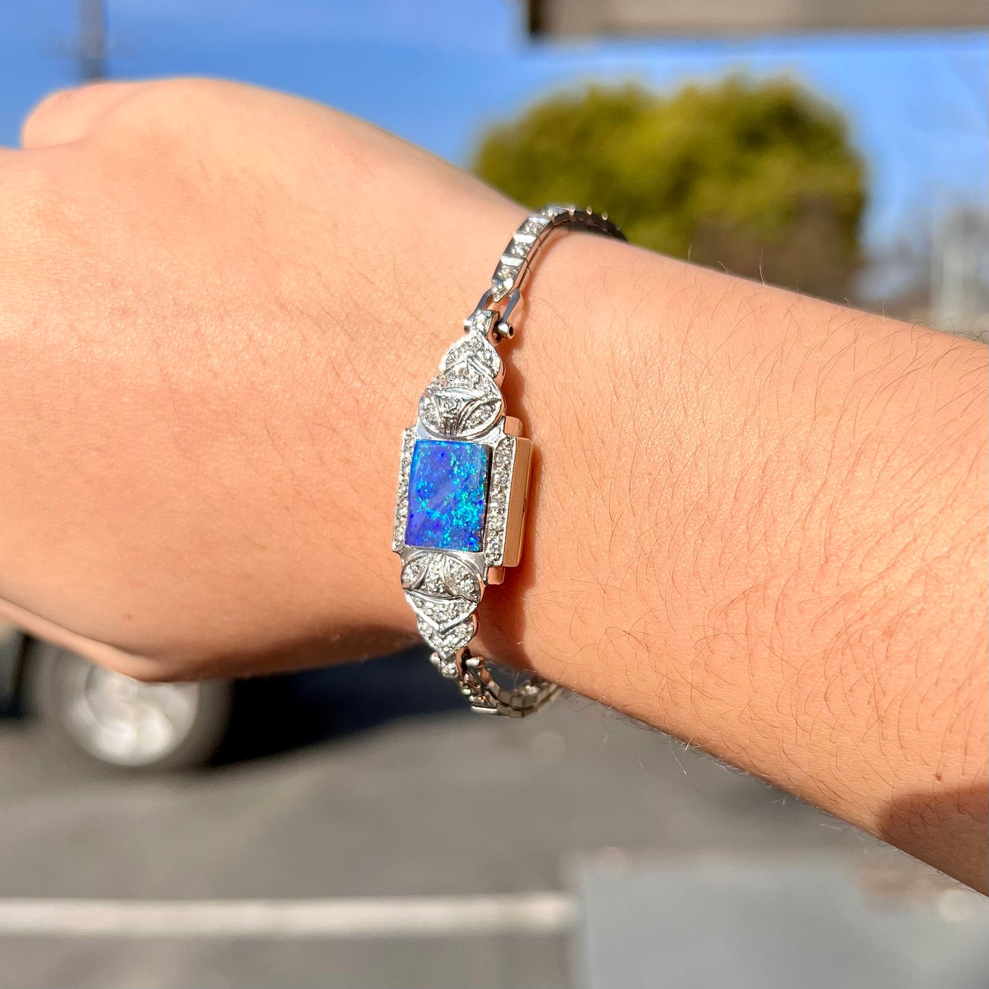 A vintage, art deco style white gold and diamond bracelet set with a rectangular shape black boulder opal stone.