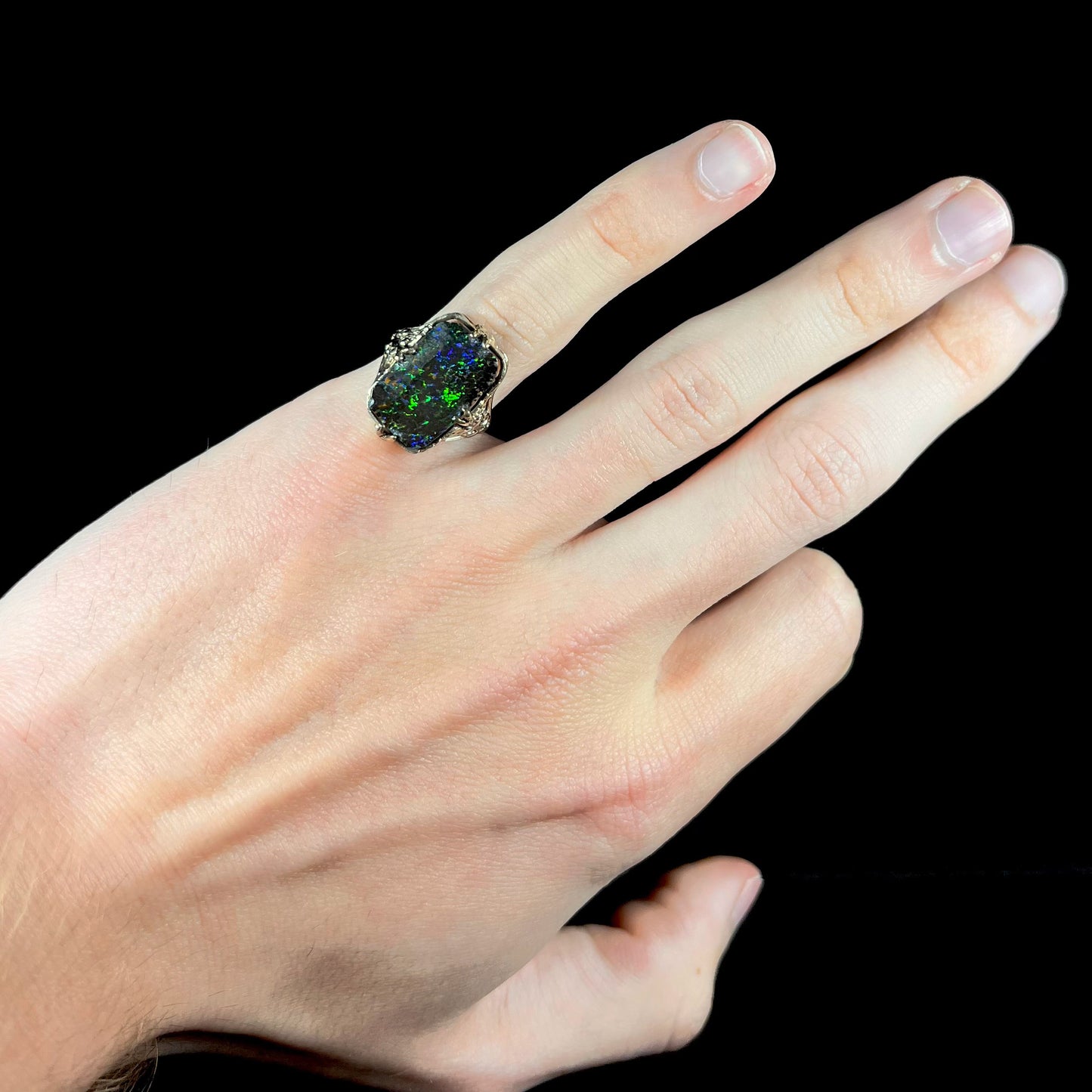 A vintage, white gold filigree unisex ring set with a natural black Koroit boulder opal.