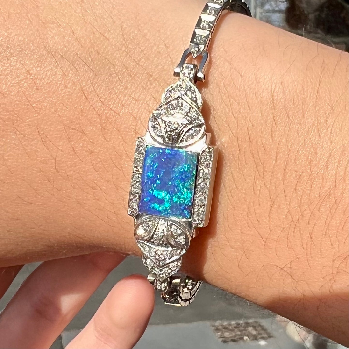 A vintage, art deco style white gold and diamond bracelet set with a rectangular shape black boulder opal stone.