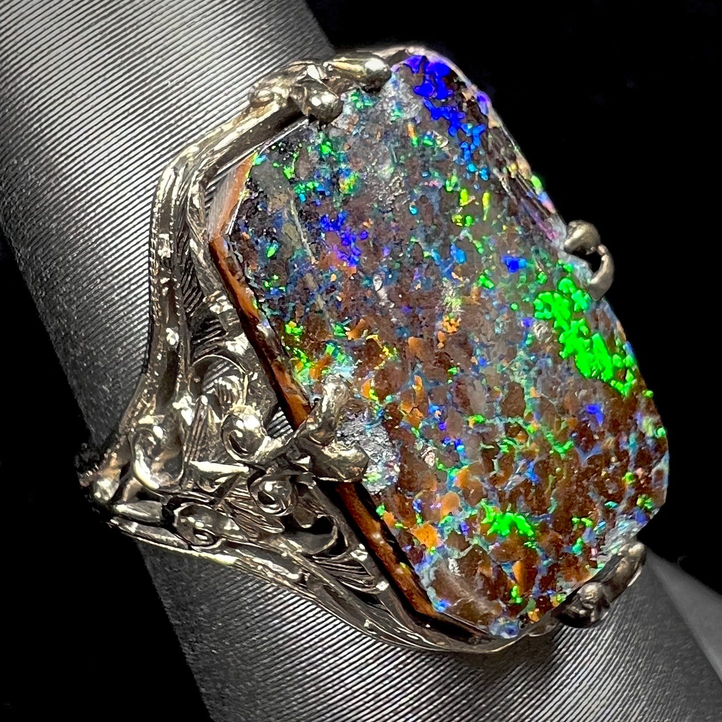 A vintage, white gold filigree unisex ring set with a natural black Koroit boulder opal.