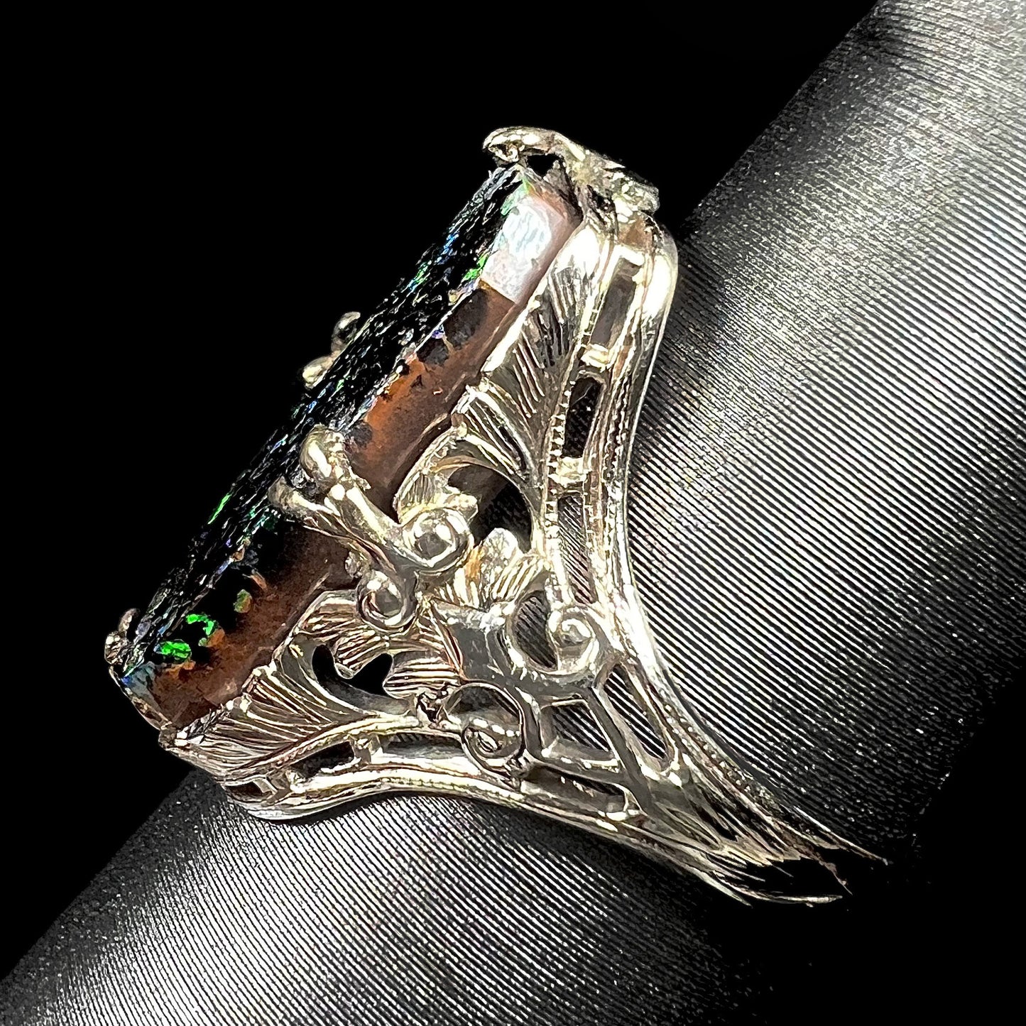 A vintage, white gold filigree unisex ring set with a natural black Koroit boulder opal.