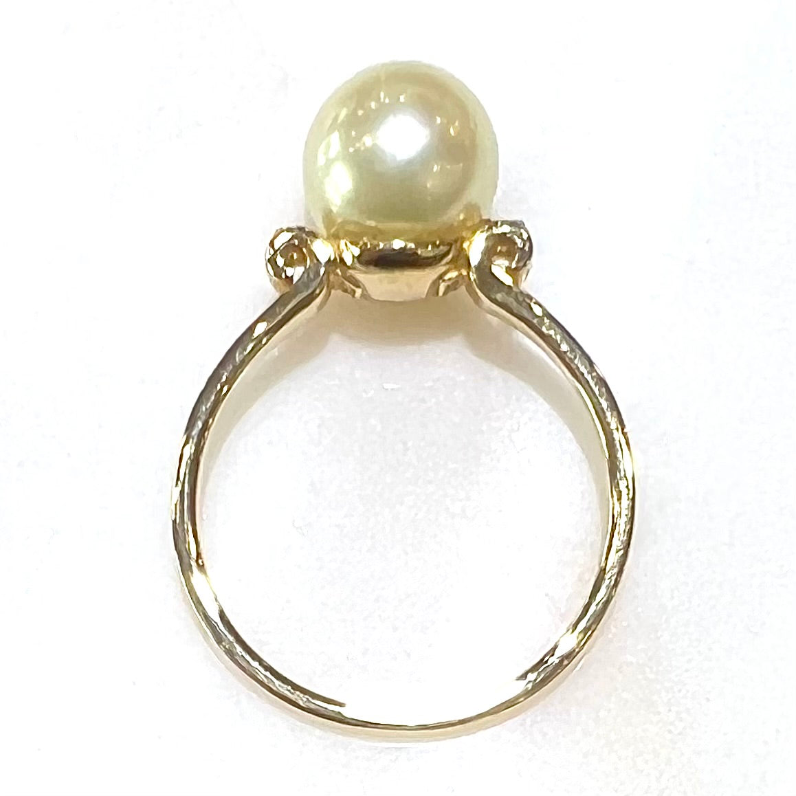 A simple, vintage, yellow gold pearl ring set with two side diamonds.