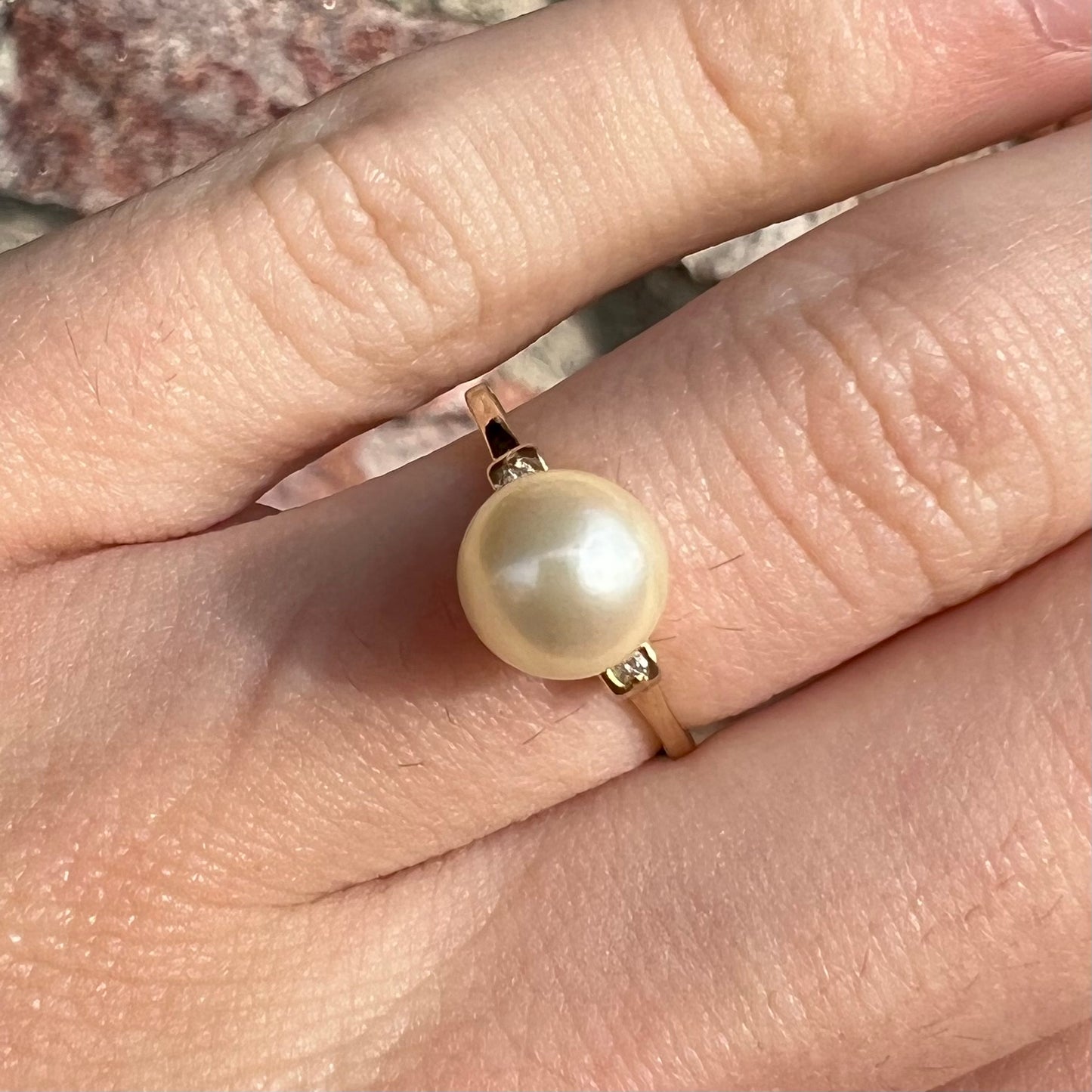 A simple, vintage, yellow gold pearl ring set with two side diamonds.