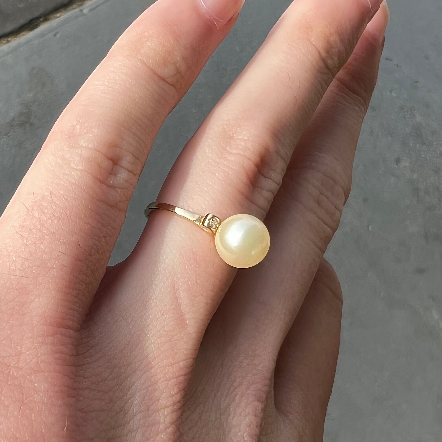 A simple, vintage, yellow gold pearl ring set with two side diamonds.