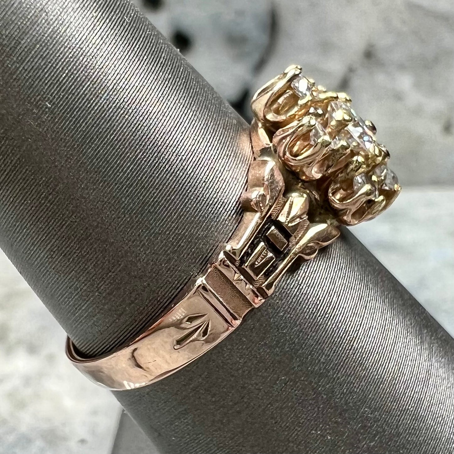 A modern Standard Round Brilliant Cut diamond set between six smaller round diamonds in an antique rose gold engagement ring setting.