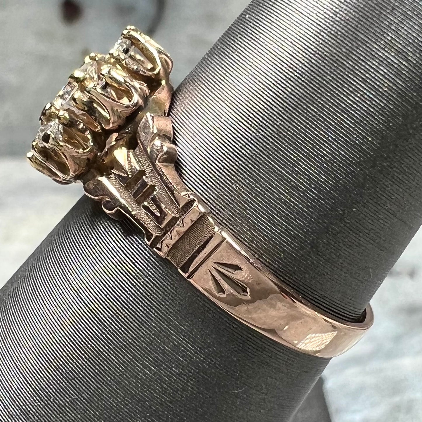 A modern Standard Round Brilliant Cut diamond set between six smaller round diamonds in an antique rose gold engagement ring setting.