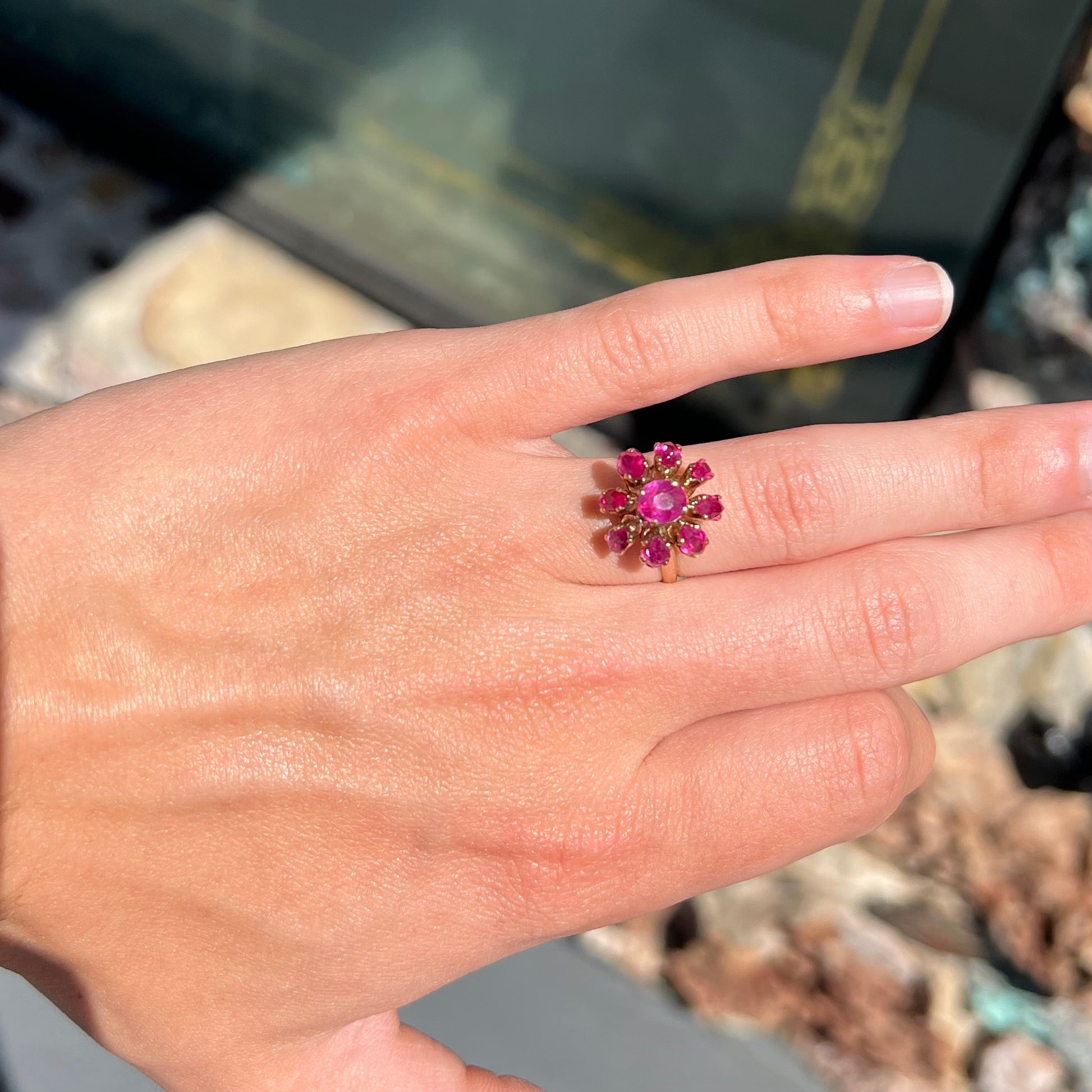 A yellow gold pink Burma ruby cluster ring with a faceted oval center stone surrounded by marquise cut stones.