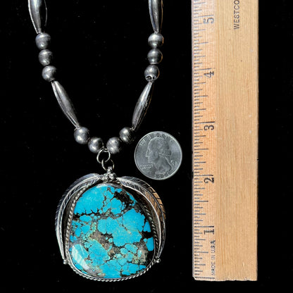 A Navajo style silver beaded necklace set with a Kingman spiderweb turquoise stone.