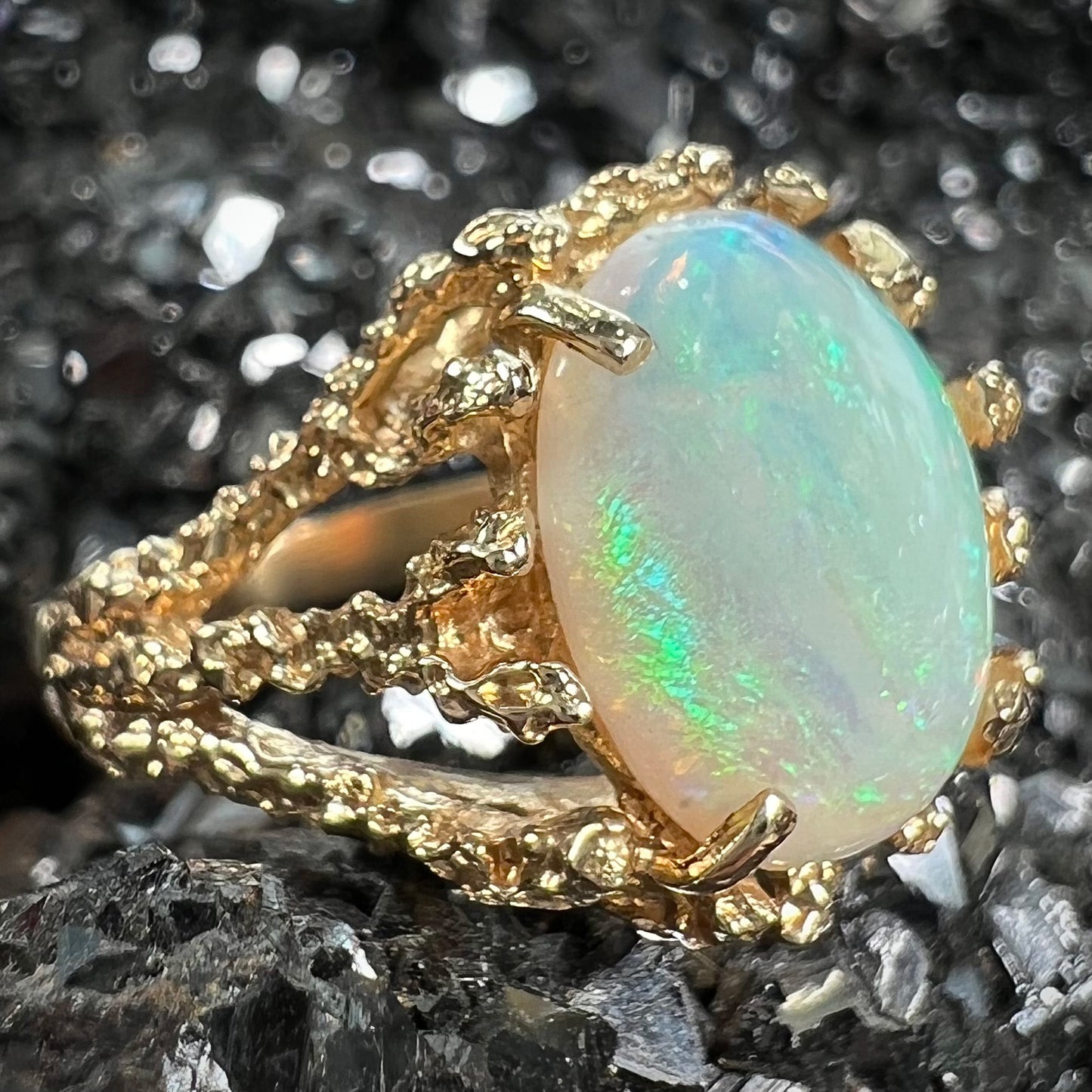 A yellow gold solitaire engagement ring set with an oval cabochon cut white crystal opal.