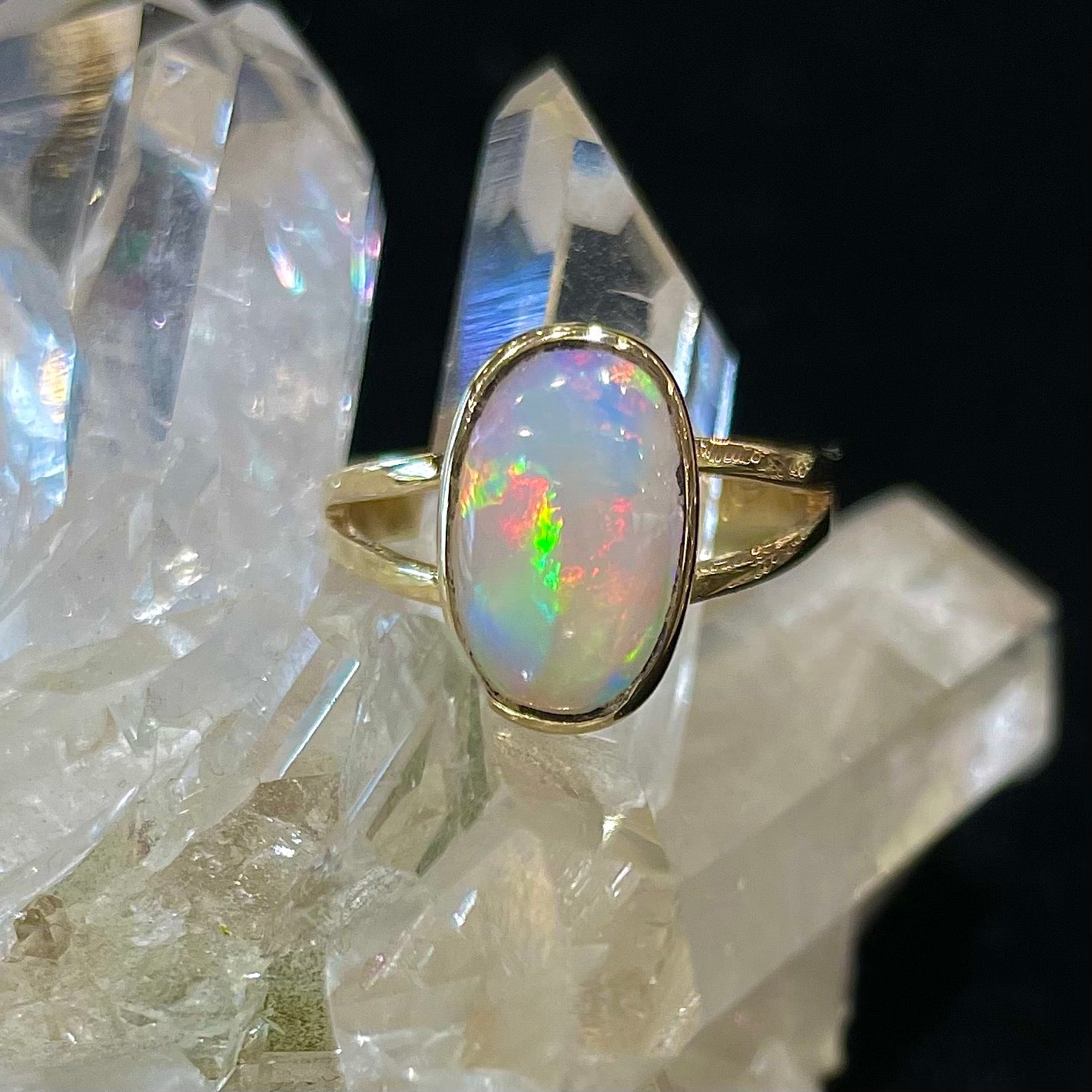 A handmade split shank white opal solitaire ring in yellow gold.