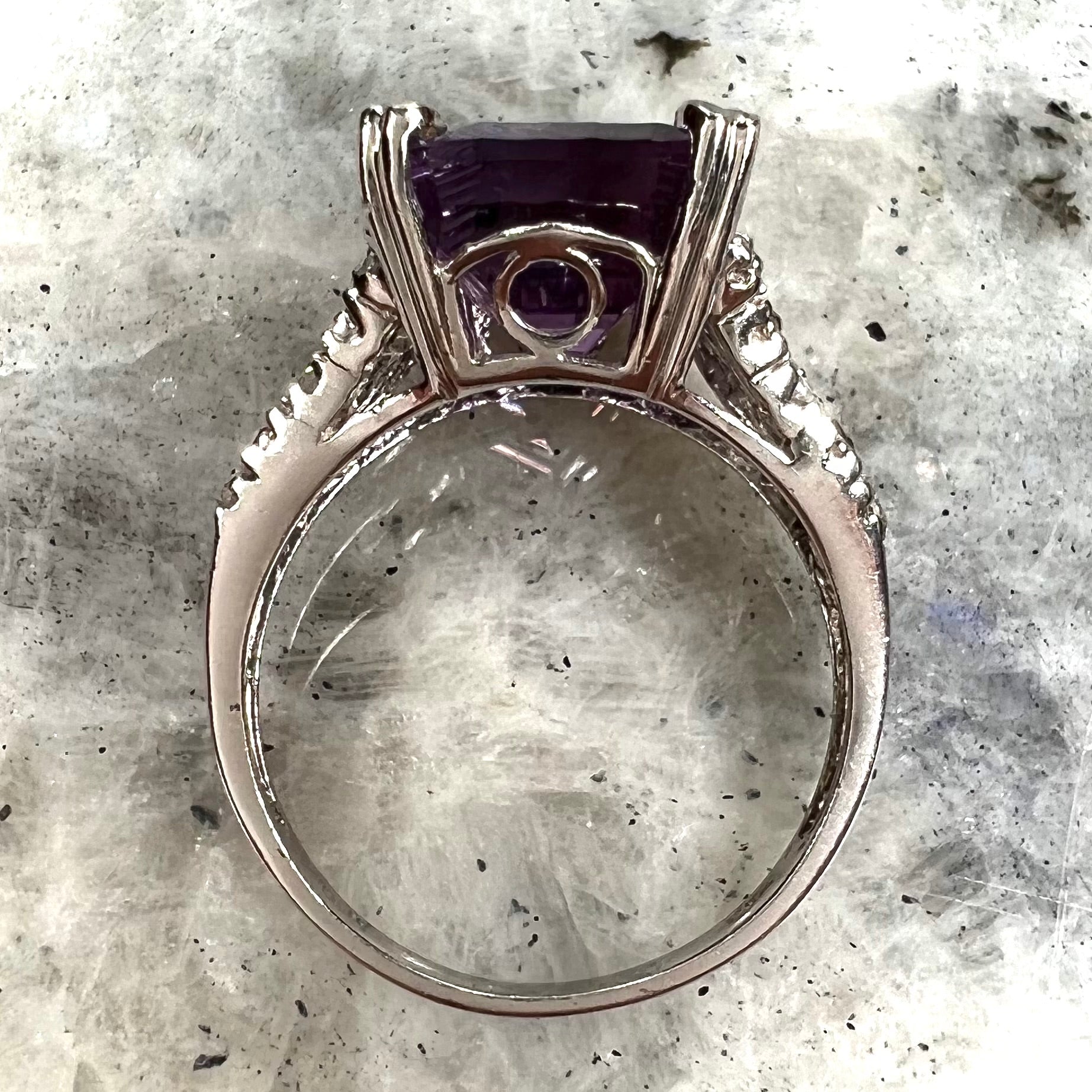 A white gold ladies ring set with an emerald laser cut amethyst and diamond chip accents.