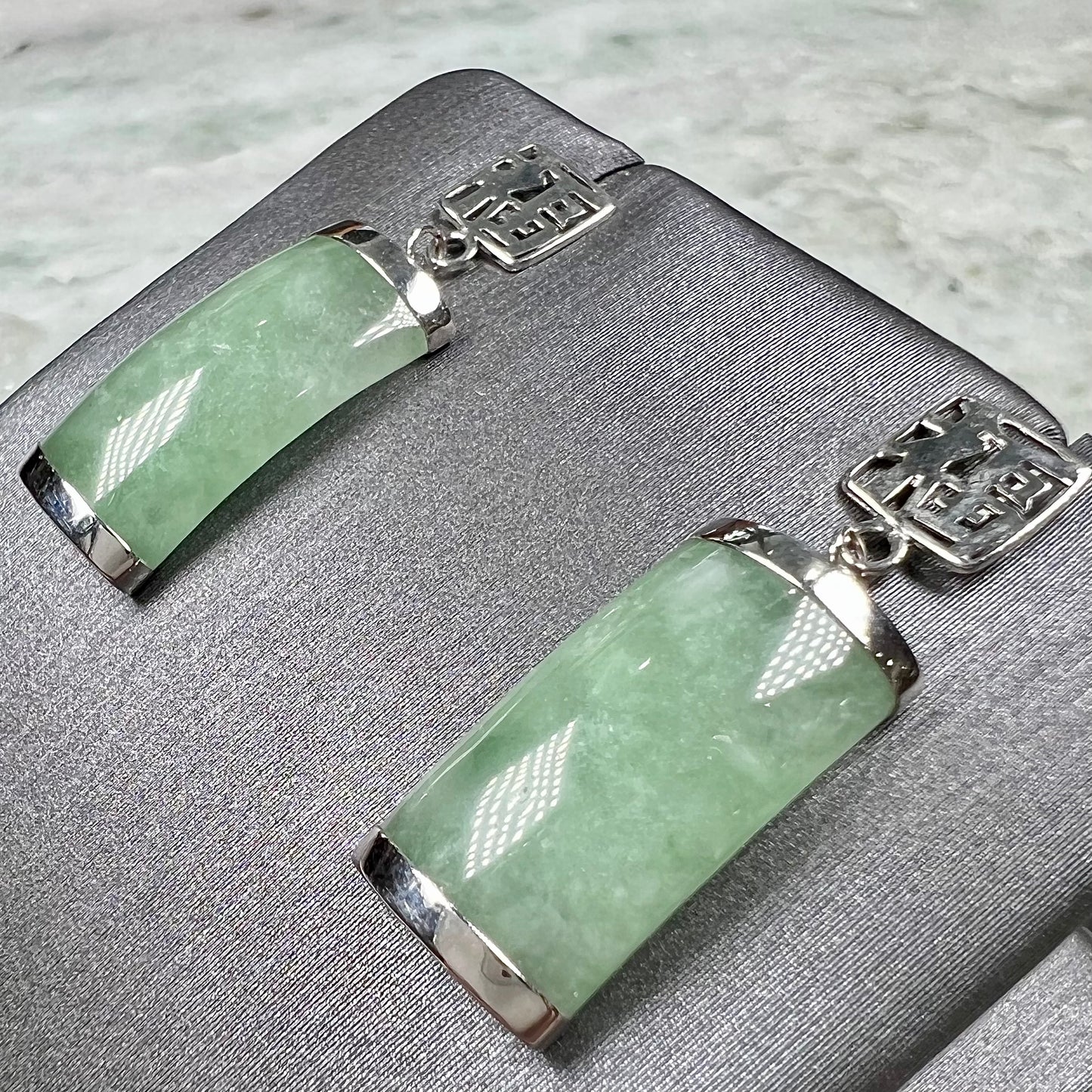 A pair of white gold jadeite dangle earrings with Chinese characters.