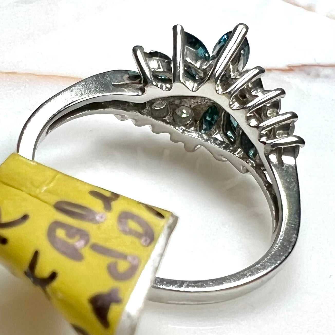 A white gold diamond cluster ring set with blue marquise cut and white round cut diamonds.