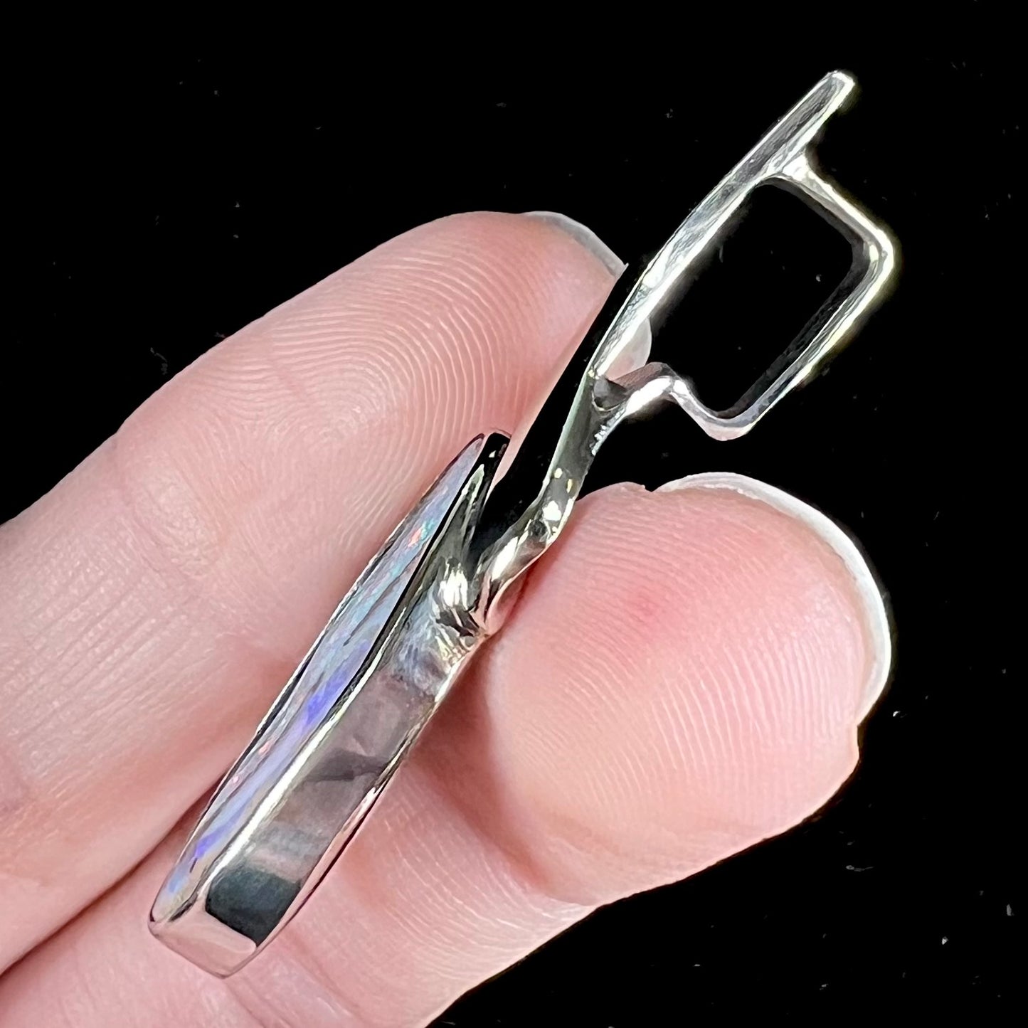 A white gold solitaire pendant set with an Quilpie, Australian boulder opal stone. The opal shines a rainbow of colors.